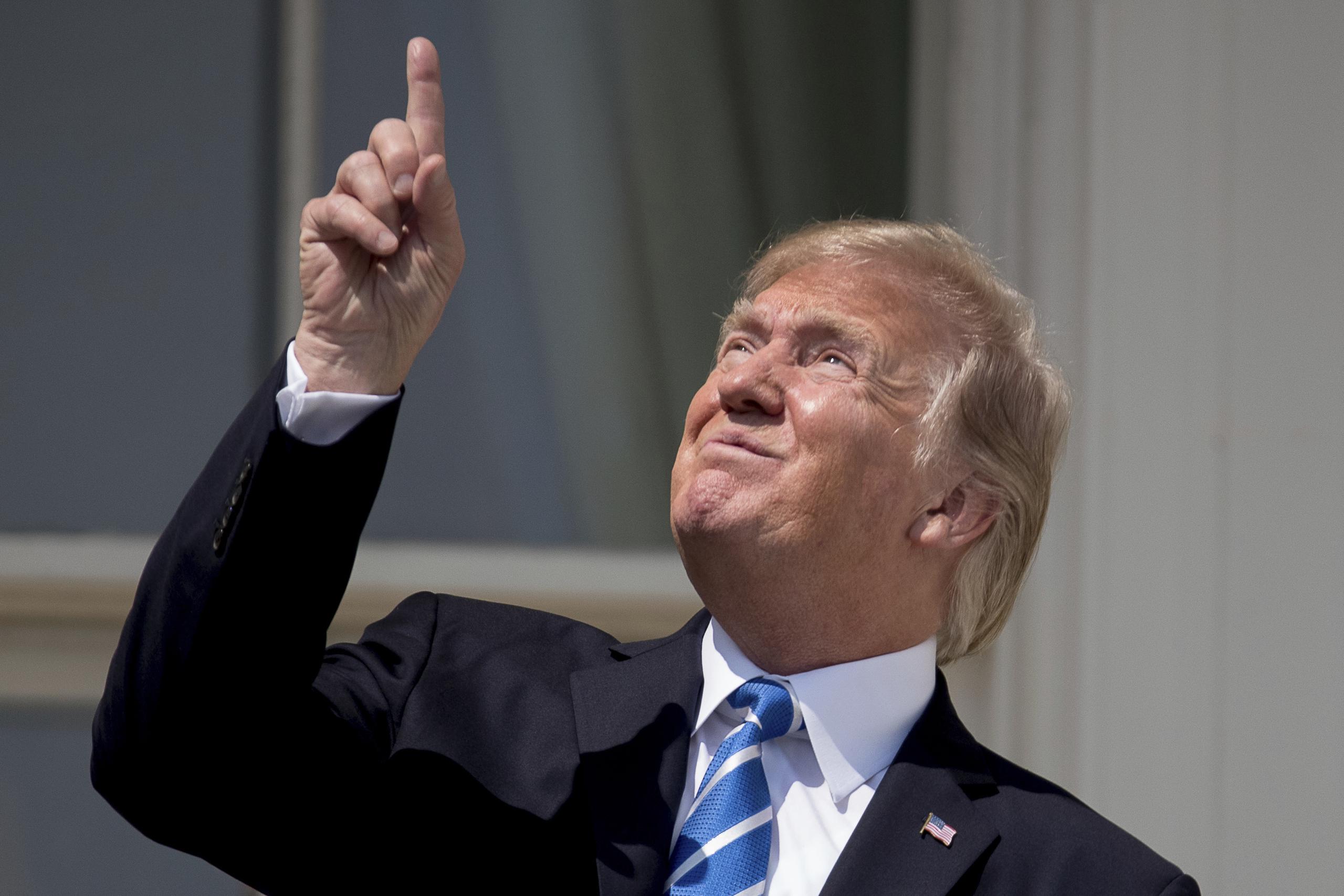 El presidente Donald Trump apuntando al sol durante un eclipse solar fuera de la Casa Blanca, en Washington