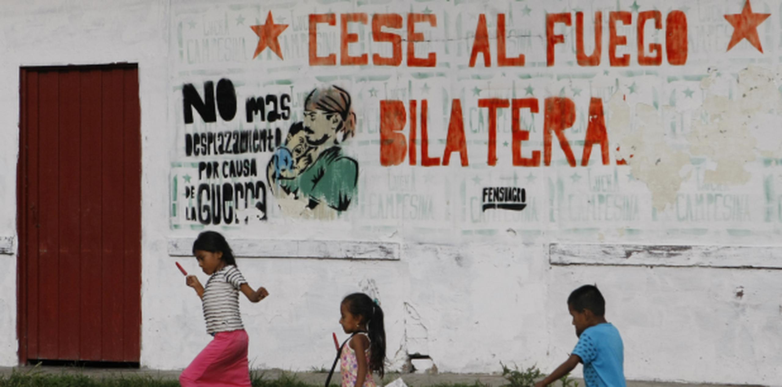 Niños colombianos juegan frente a un letrero alusivo al cese al fuego definitivo en la localidad de El Paulo, departamento de Cauca. (EFE/Christian Escobar Mora)