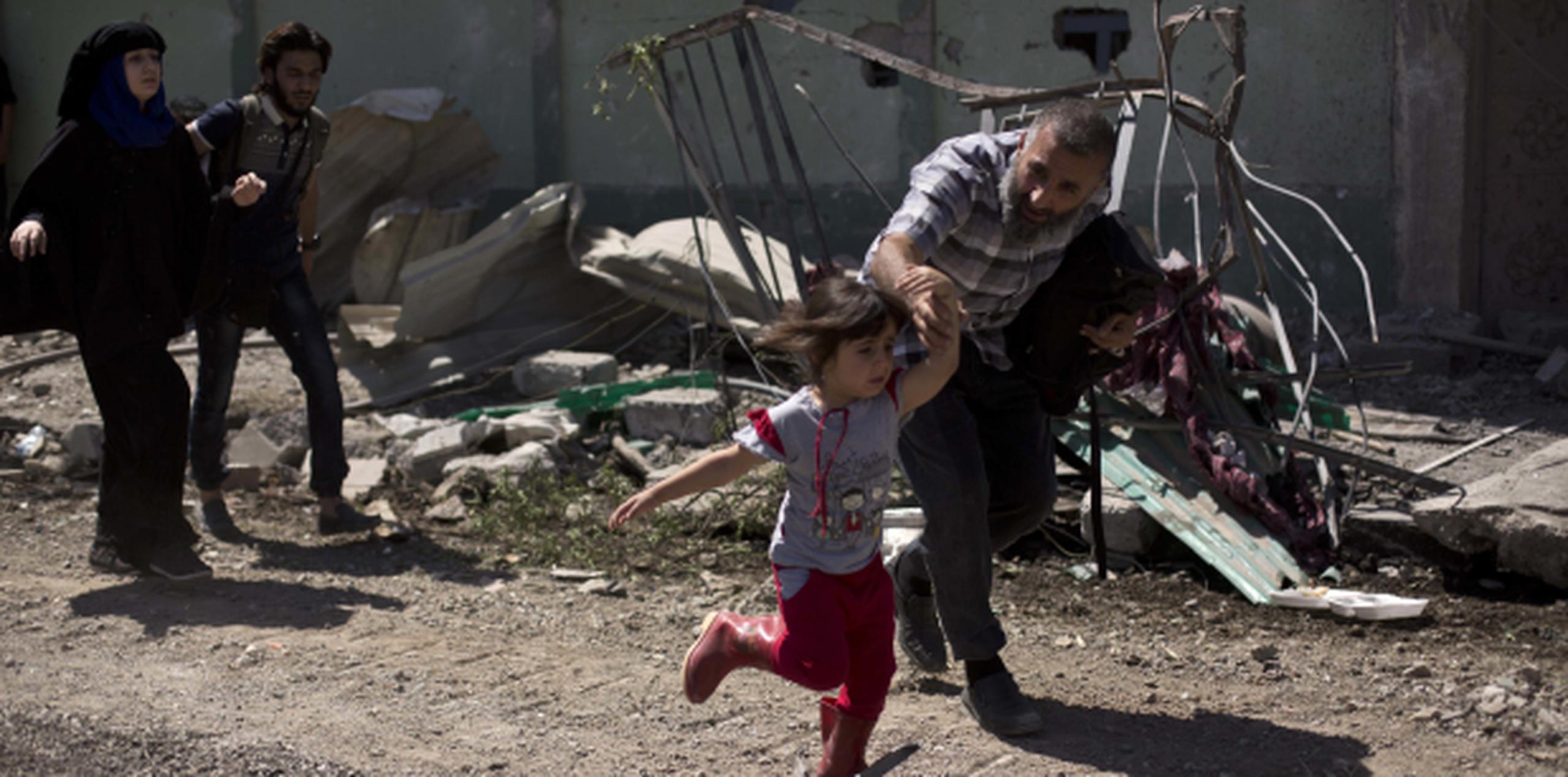 Un hombre y un niño corren en medio de un ataque reciente en Mosul, Irak. (AP)