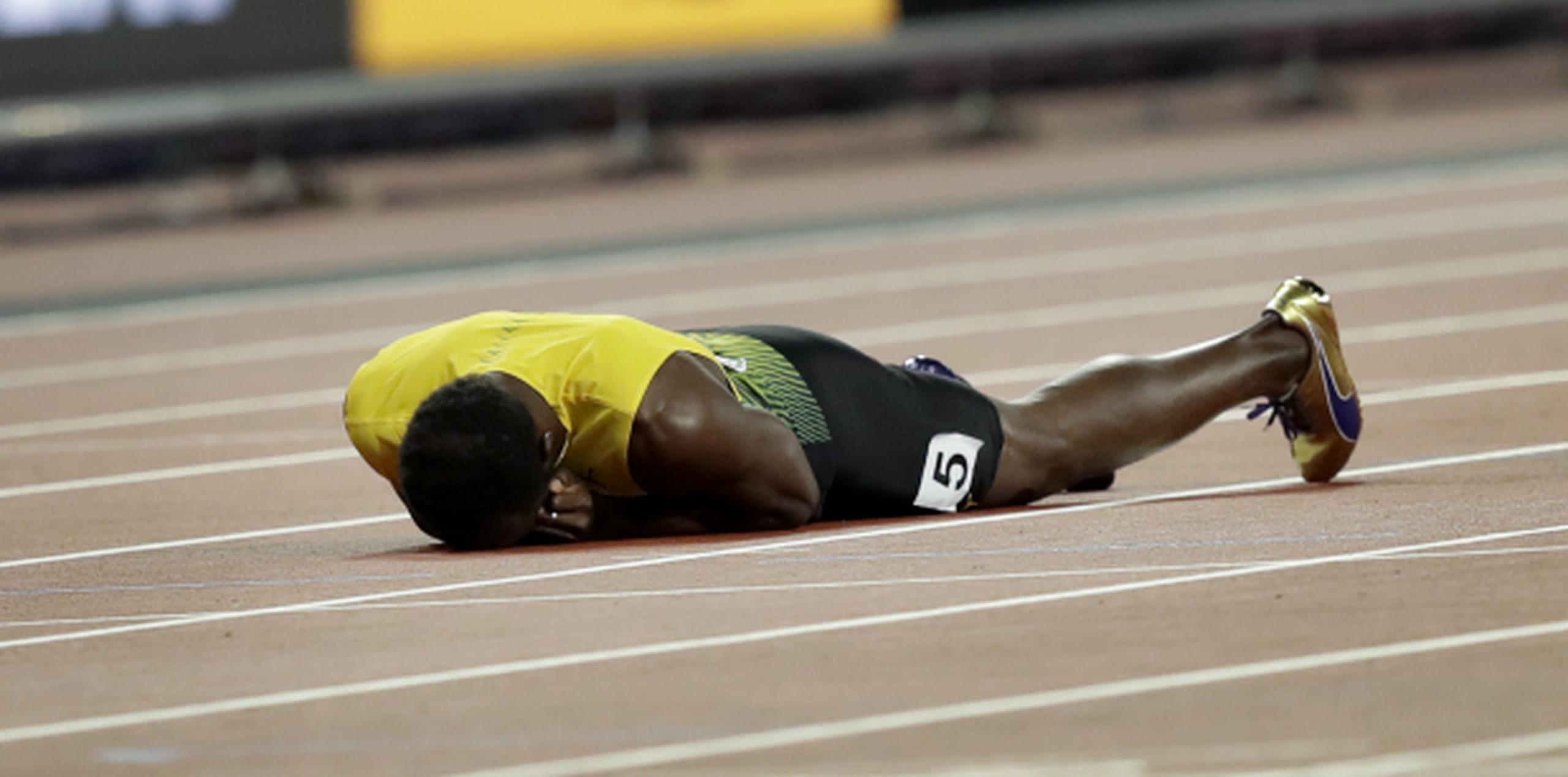Usain Bolt tirado en el suelo tras lastimarse. (AP / Tim Ireland)