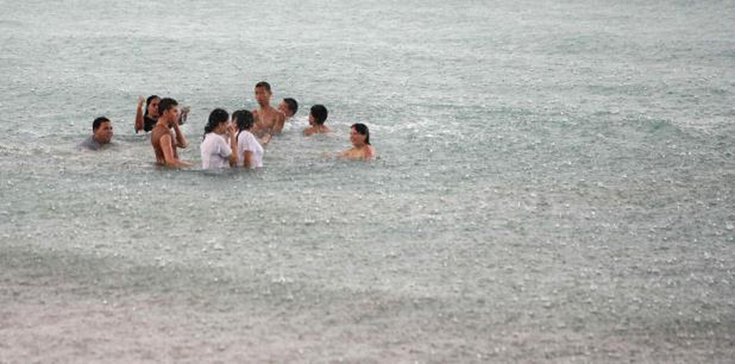 Un grupo de personas permanece en el mar a pesar de la lluvia. (Archivo)