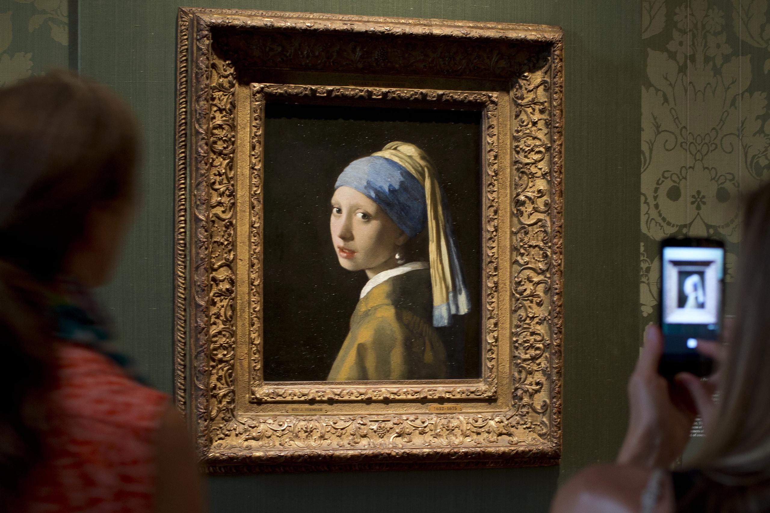 Visitantes toman fotos del cuadro de Johannes Vermer "Niña con un arete de perla" en el museo Mautishuis de La Haya, Holanda.