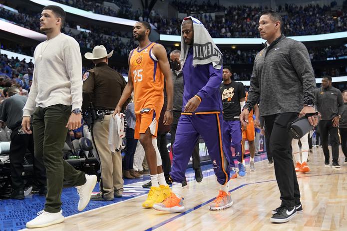 El delantero de los Suns, Mikal Bridges (25), y el armador Chris Paul, con una toalla sobre su cabeza, caminan hacia el camerino al cierre del partido del domingo en Dallas.