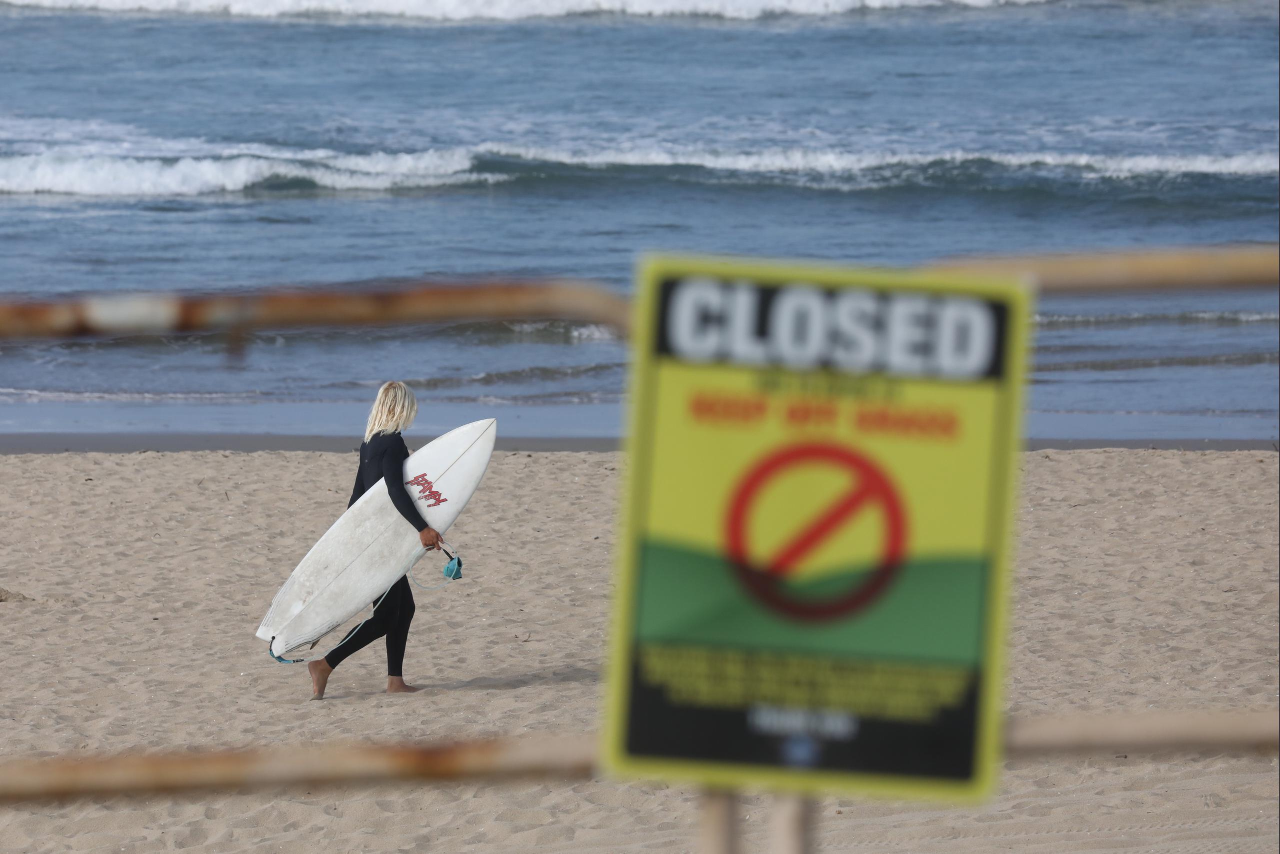 Una surfista camina hacia el agua este viernes en Huntington Beach, California