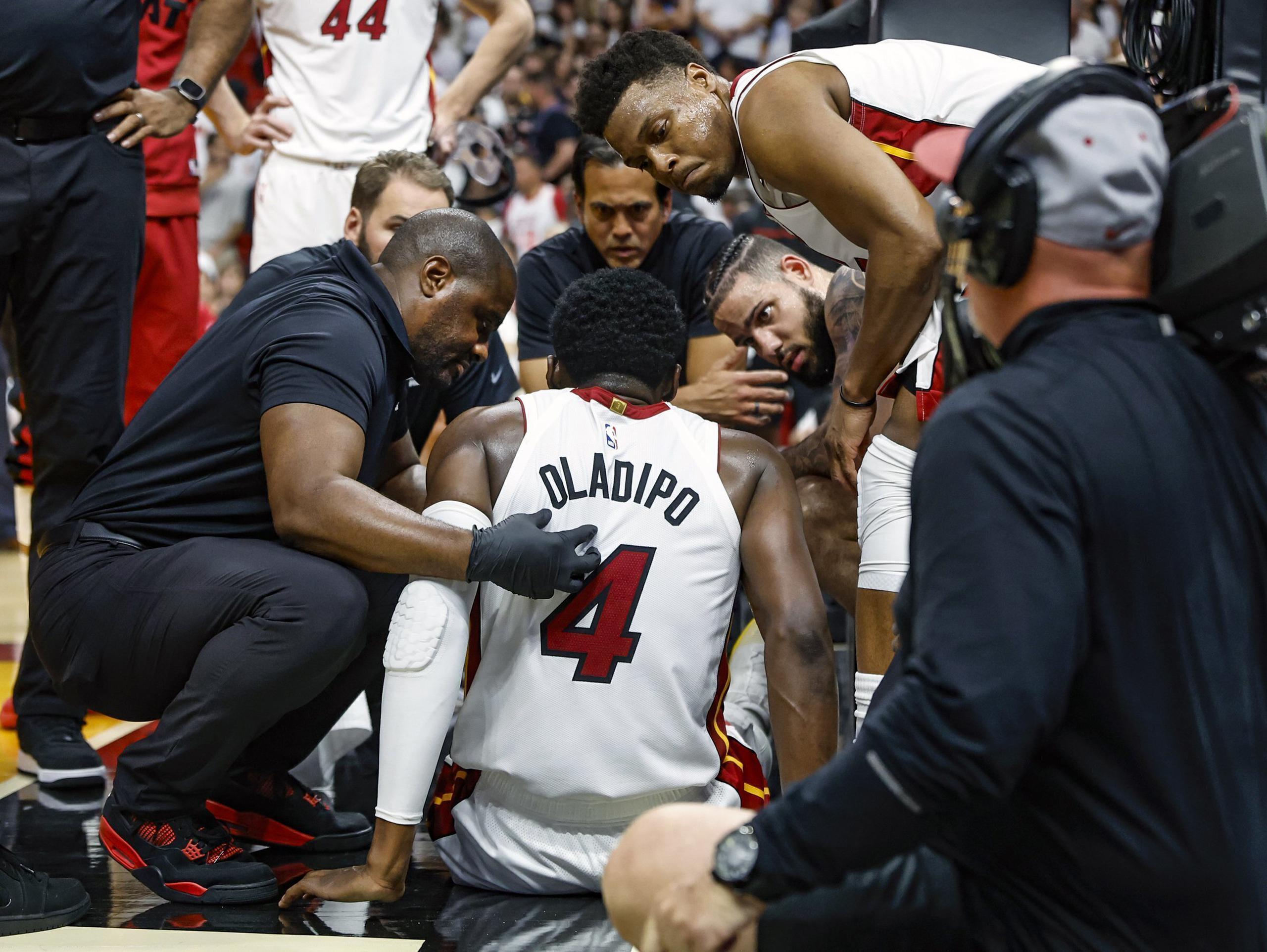 Compañeros y personal del Heat de Miami atienden a Victor Oladipo (4) que sufrió una lesión en un juego ante los Bucks de Milwaukee, el sábado 22 de abril de 2023, en Miami. (Al Diaz/Miami Herald vía AP)