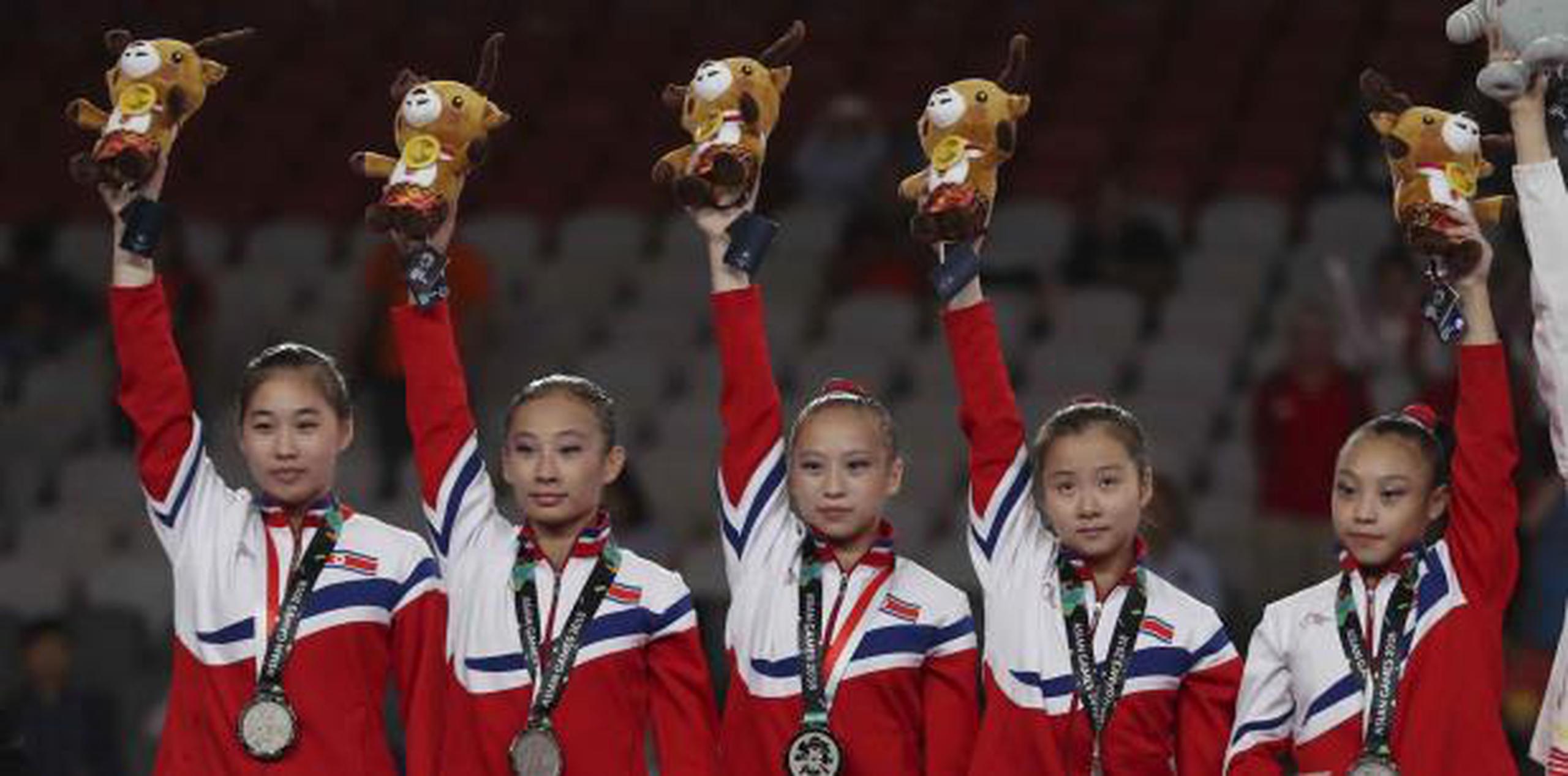 El equipo femenino de gimnasia de Corea del Norte celebra sus medallas de plata en los XVIII Juegos Asiáticos, en Yakarta, Indonesia. (AP / Dita Alangkara)