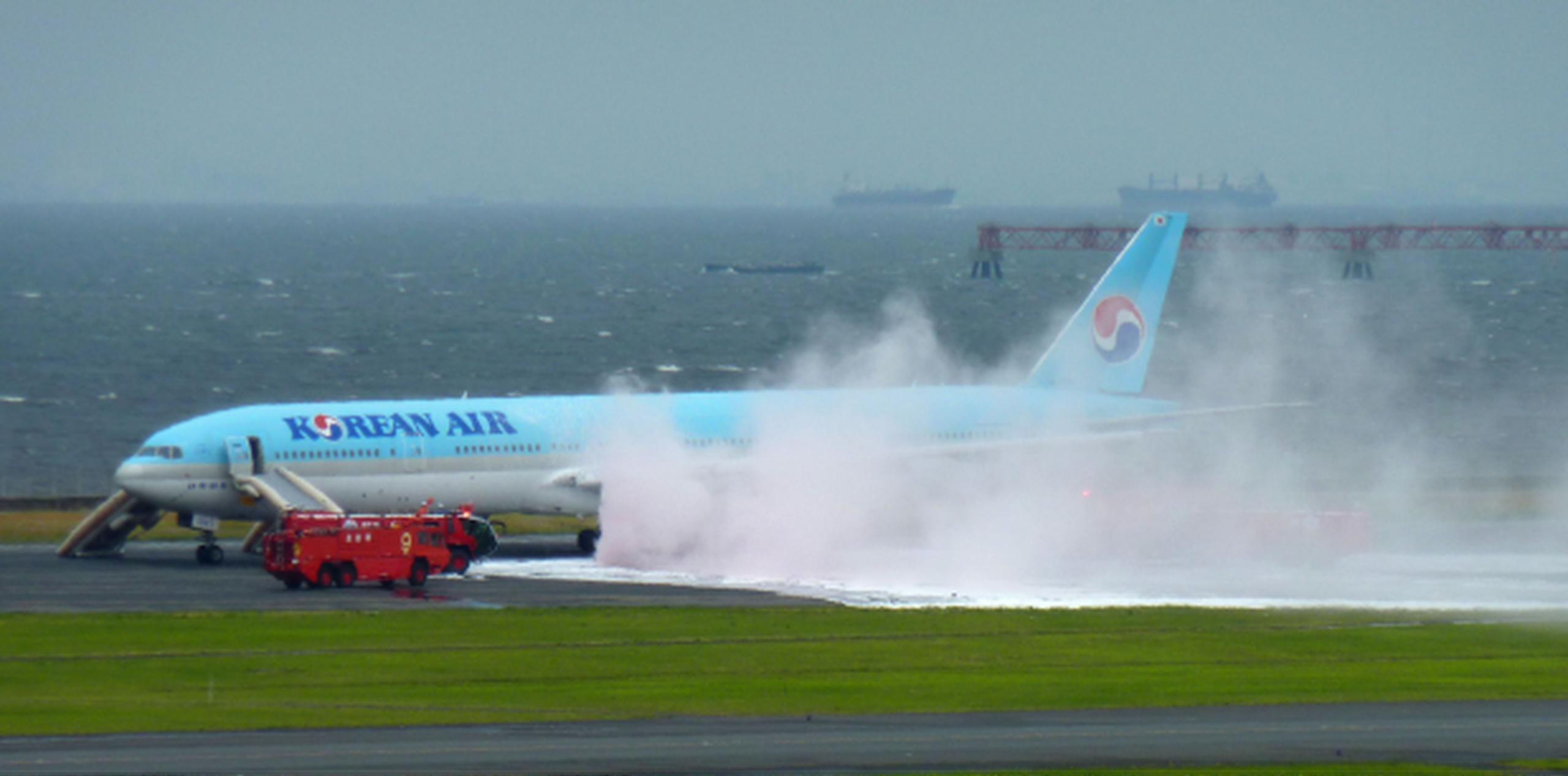 Bomberos se apreuran a apagar el fuego en uno de los motores de la areonave de Korean Air que se accidentó en la pista del aeropuerto de Haneda, en Tokio. (AP)
