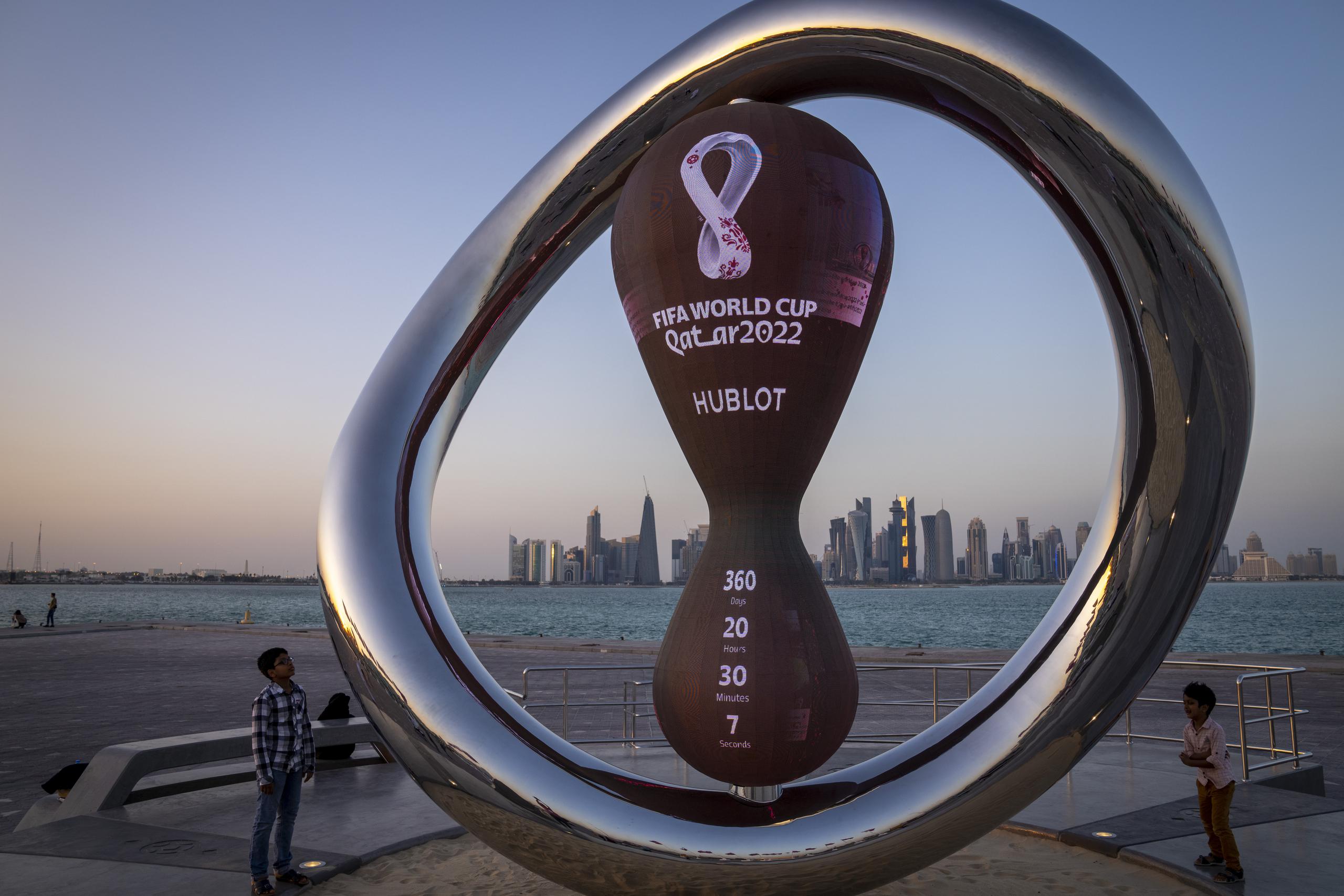 Un par de niños observan el reloj que marca la cuenta regresiva hacia el Mundial de Qatar en Doha.