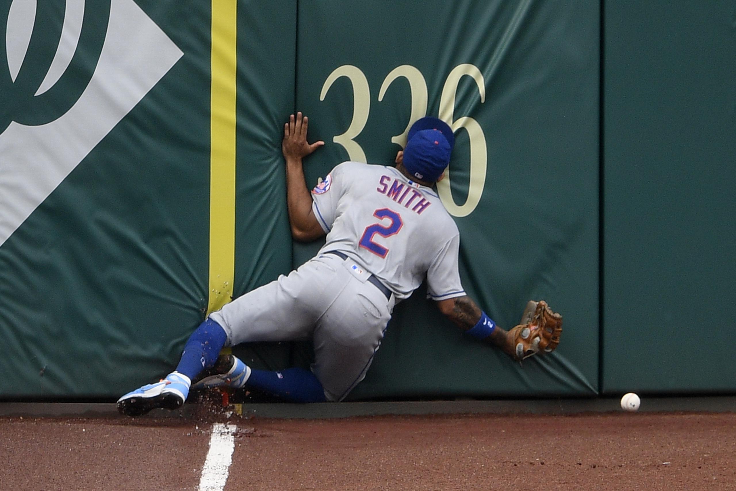 Dominic Smith, de los Mets, se estrella con la pared del jardín izquierdo en intento de atrapar un batazo de Andrew Stevenson en la quinta entrada.