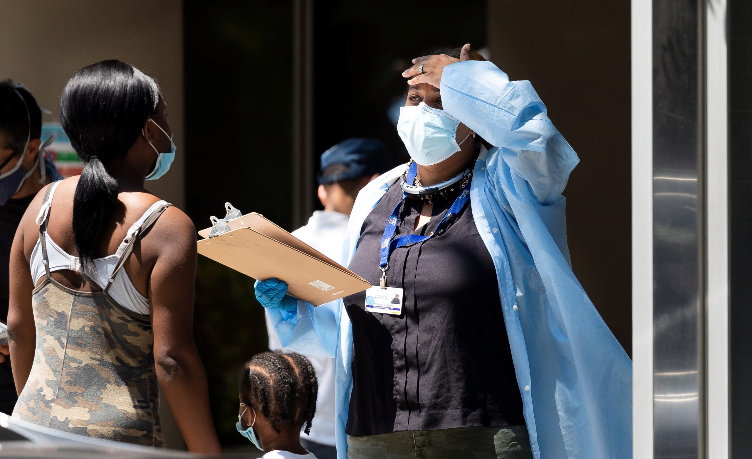 Una trabajadora de atención médica habla con una paciente fuera de una zona de prueba COVID-19 administrada por la ciudad en Nueva York