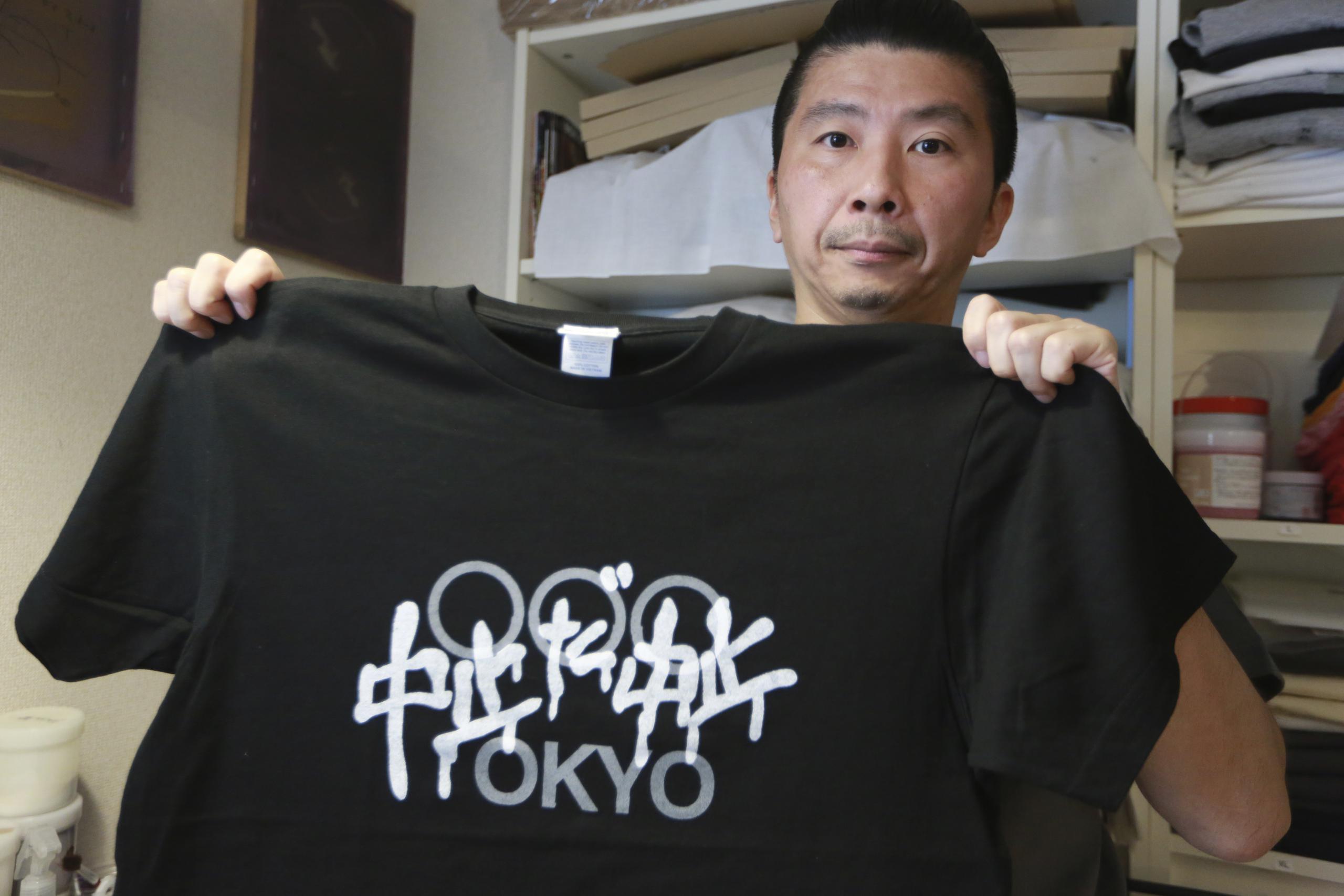 El diseñador Susumu Kikutake, quien muestra una camiseta antiolímpica, dijo que la demanda por estas piezas se ha multiplicado.
