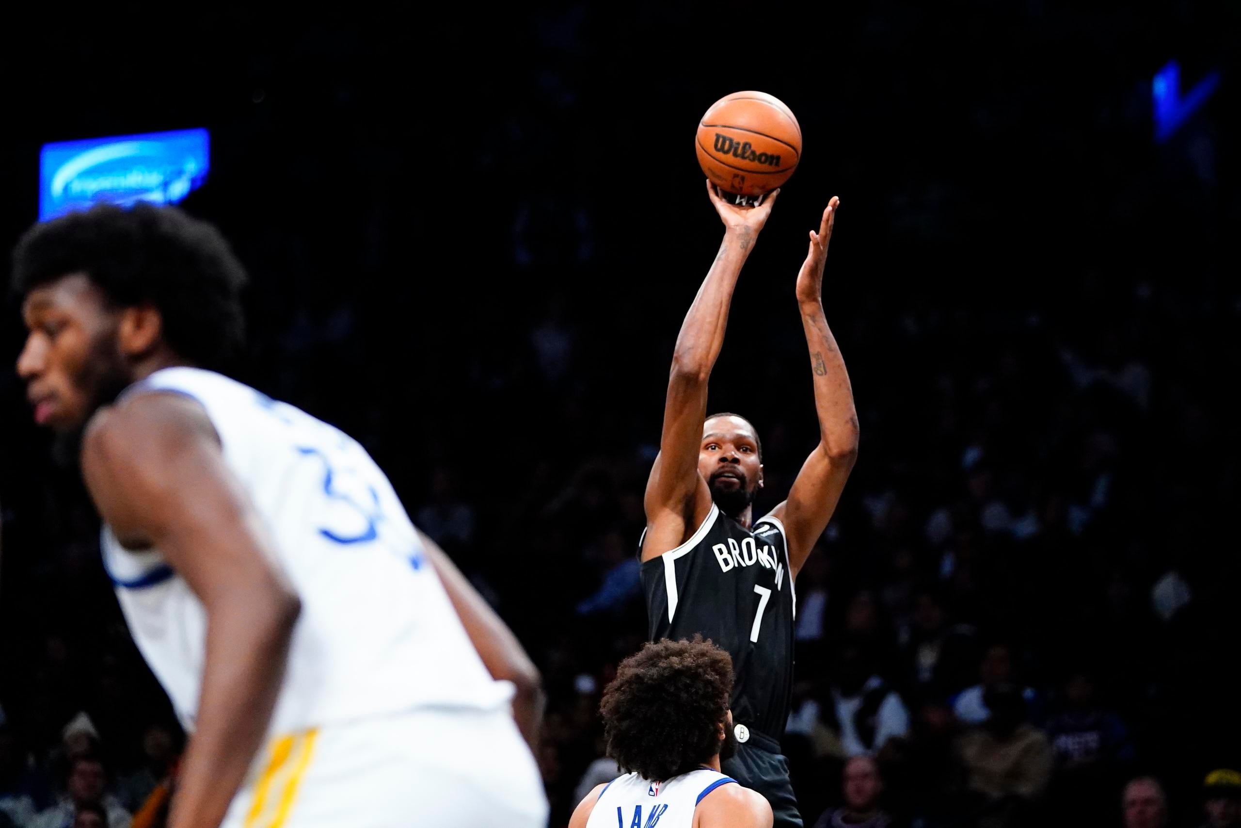Kevin Durant, de los Nets de Brooklyn, dispara frente a Anthony Lamb, de los Warriors de Golden State, en el encuentro del miércoles. Durant fue el mejor anotador de los Nets con 23 puntos.