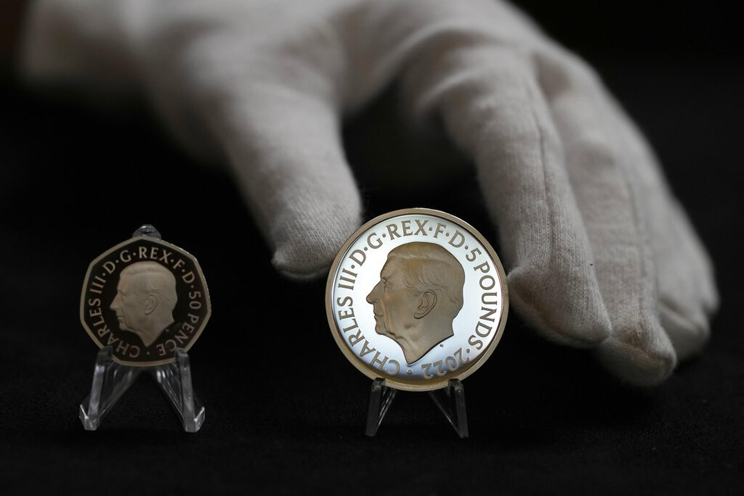 Dos monedas nuevas muestran el retrato oficial del rey Carlos III: una de 50 peniques a la izquierda y una de 5 libras a la derecha.