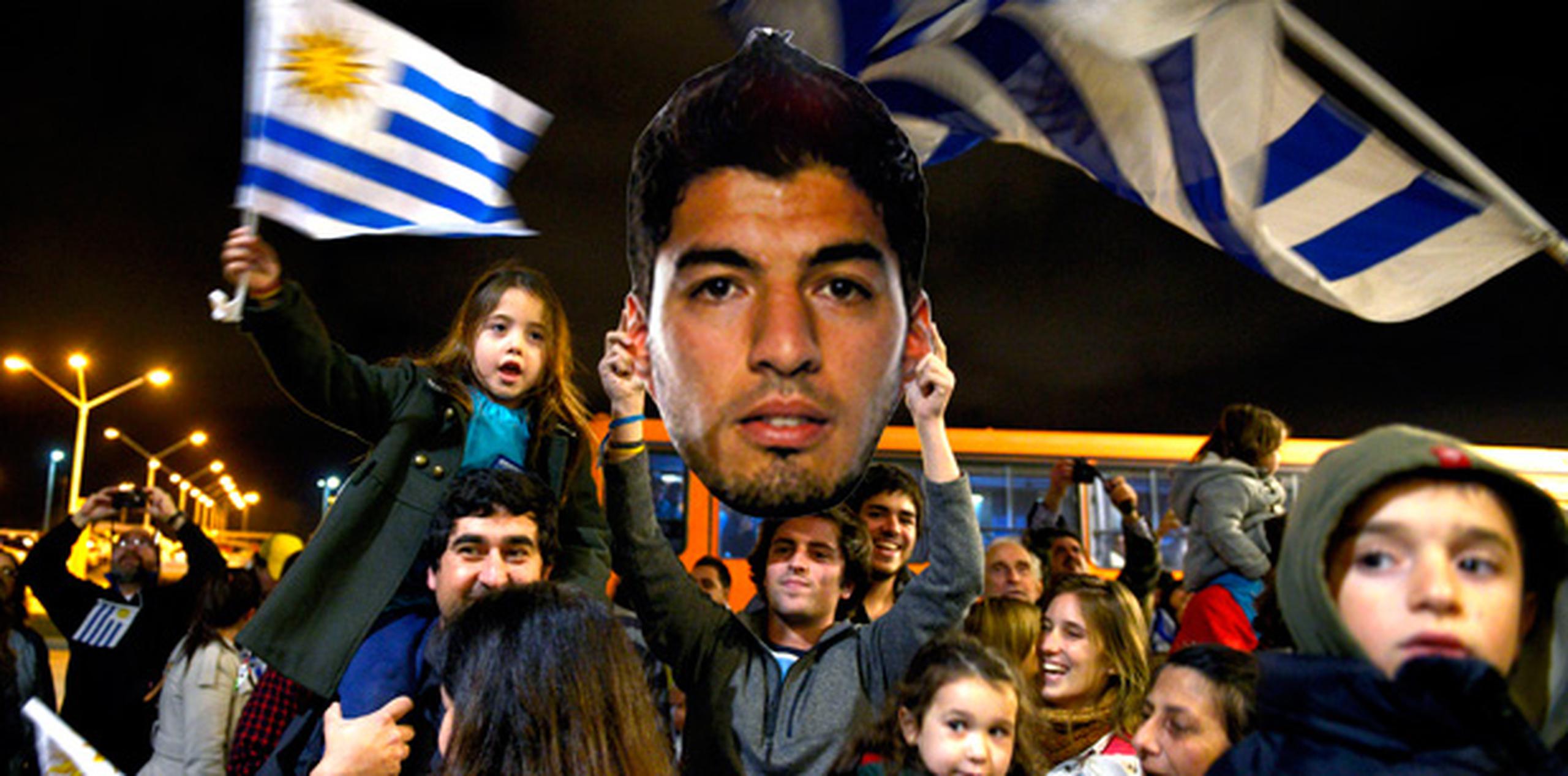 Unas mil personas con banderas de Uruguay y carteles críticos hacia la FIFA se habían congregado desde la tarde del jueves en la zona del aeropuerto para darle su apoyo a Suárez, suspendido ese mismo día por cuatro meses por morder al italiano Giorgio Chiellini en la Copa del Mundo de Brasil. (AP)