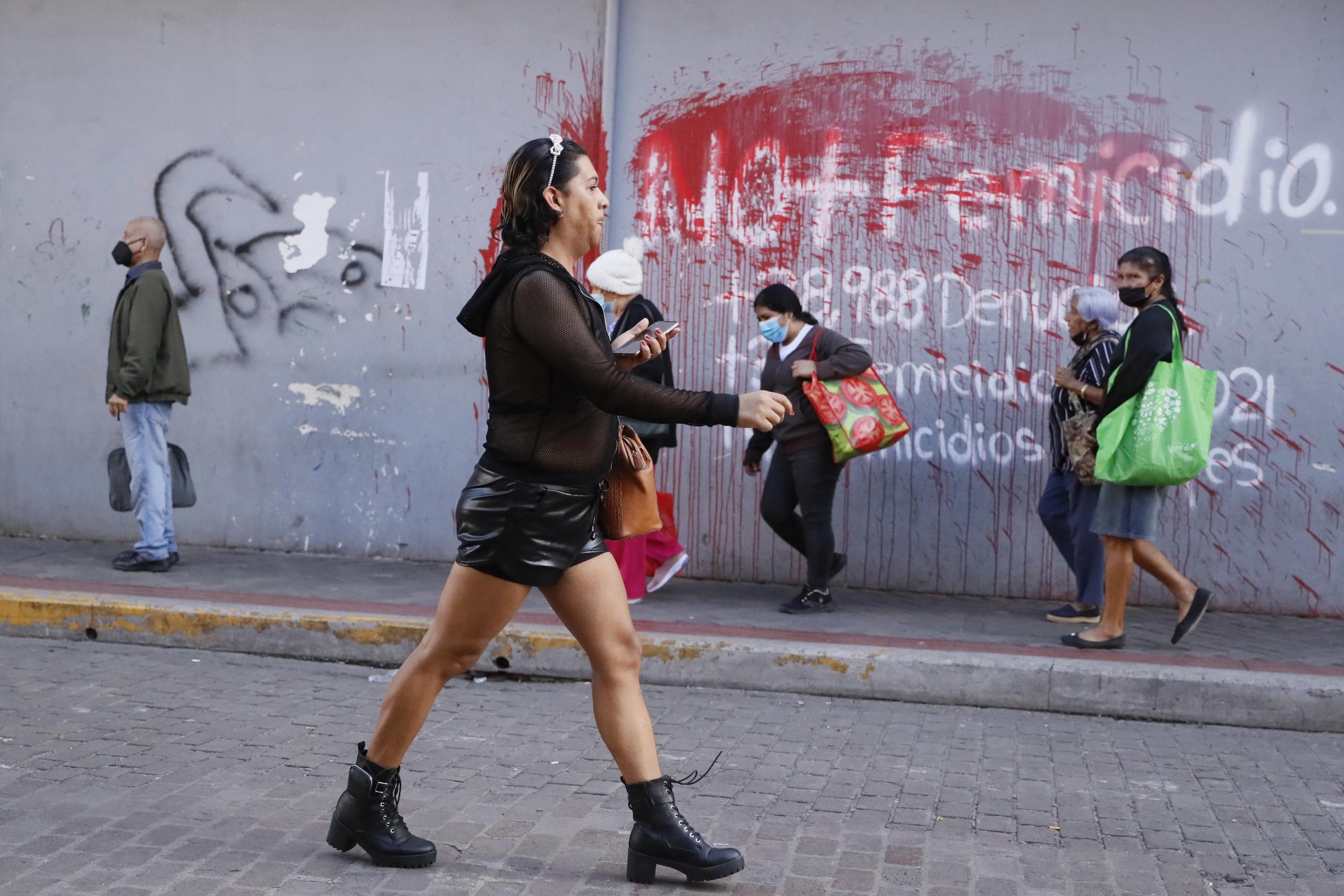 Elle de la comunidad LGBTI camina frente a un aviso pintado en una pared en contra del femicidio hoy en Tegucigalpa (Honduras). EFE/Gustavo Amador

