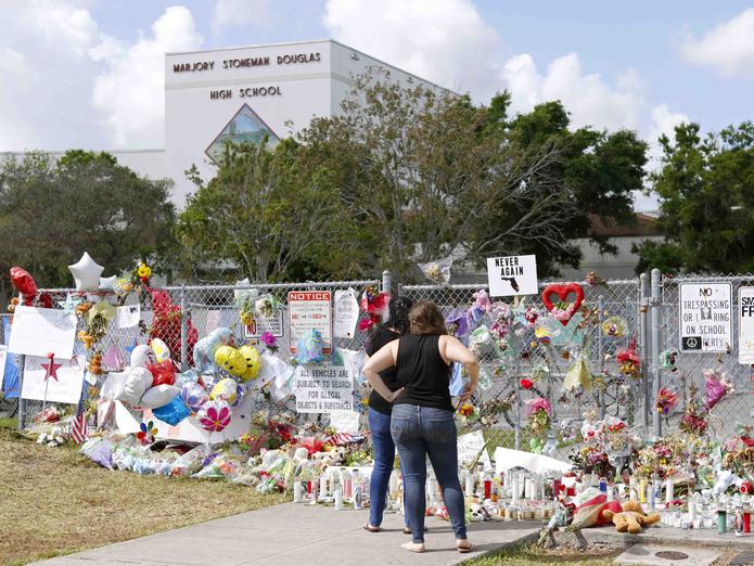 Dos personas observan un altar improvisado en memoria de las víctimas del tiroteo en la Escuela Secundaria Marjory Stoneman Douglas en Parkland, Florida. (AP)