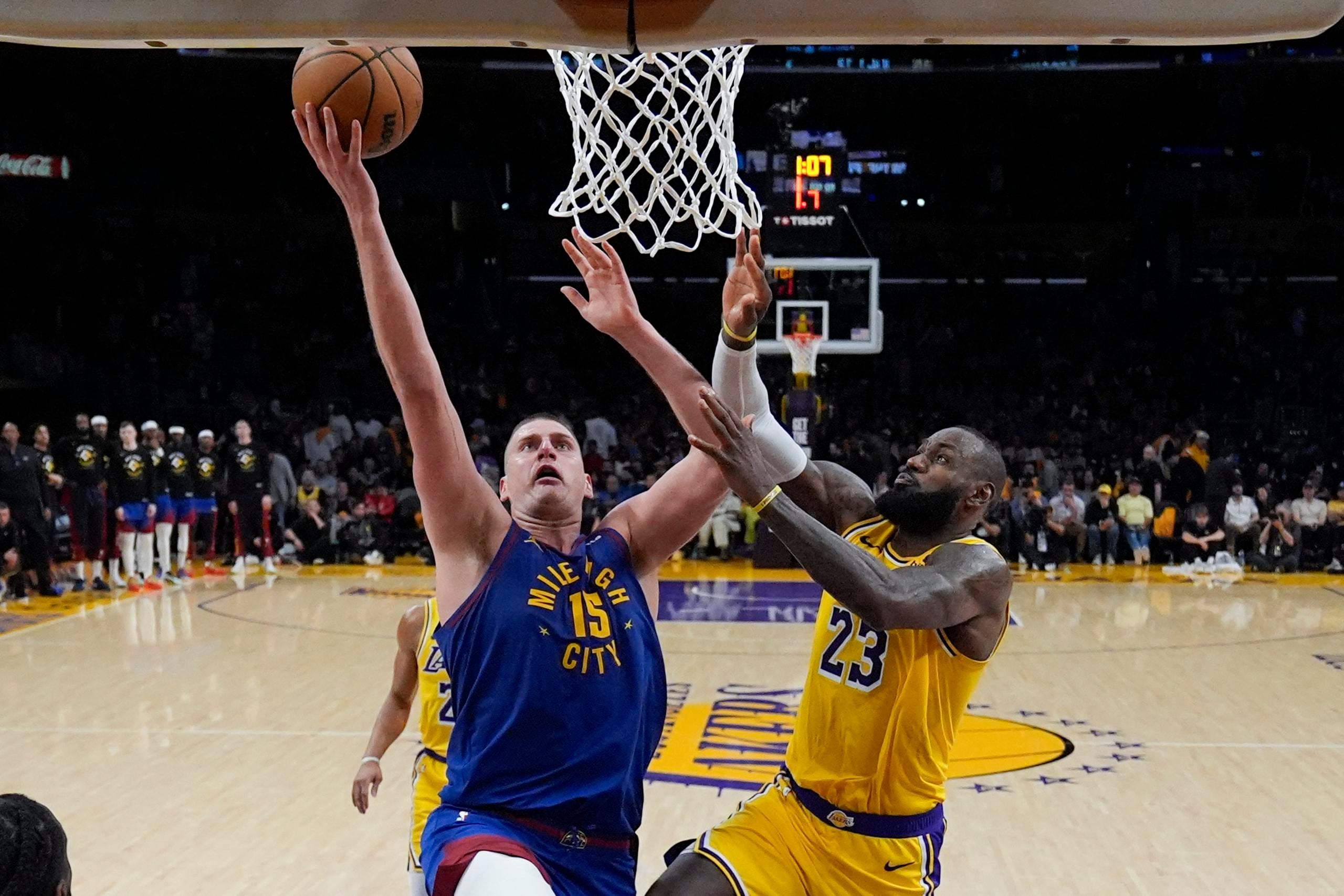 Nikola Jokic, de los Nuggets de Denver, busca a anotar frente a LeBron James, de los Lakers de Los Ángeles.