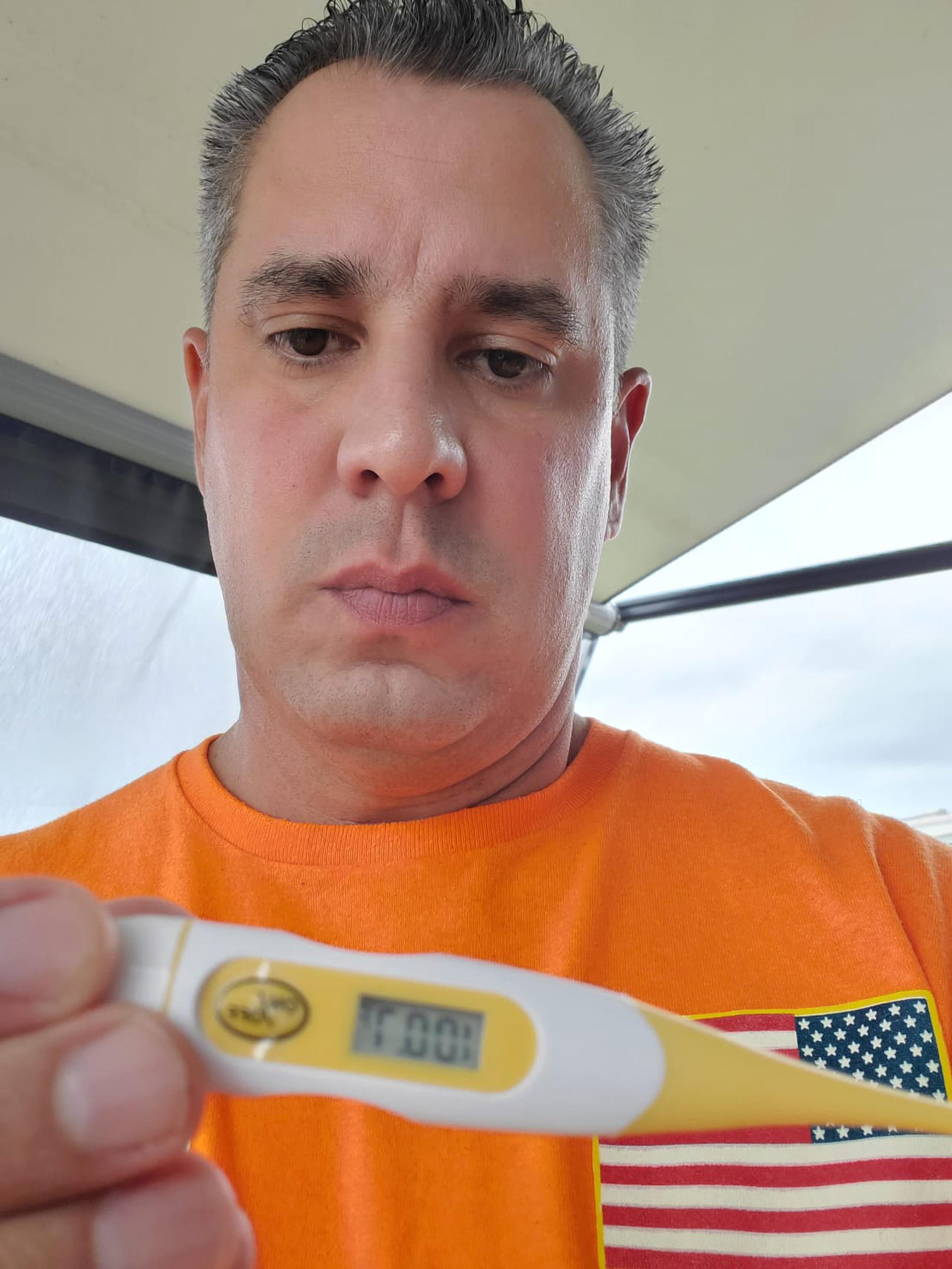 Anthony Irizarry muestra un termómetro digital con su temperatura corporal al siguiente día de haber obtenido la segunda dosis de la vacuna experimental.