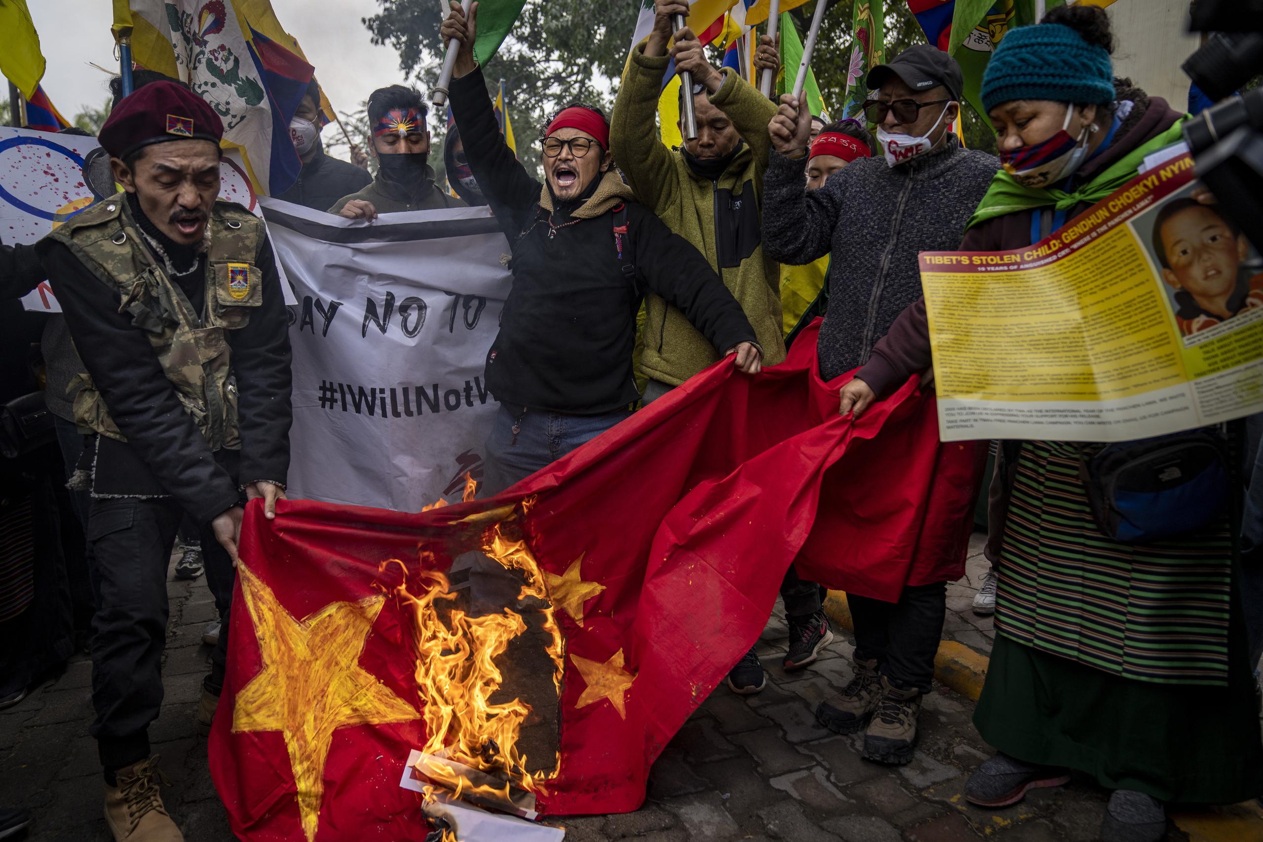Tibetanos exiliados queman una bandera de China durante una protesta contra los Juegos Olímpicos de Invierno de Beijing, en Nueva Delhi, India, el 4 de febrero de 2022. (AP Foto/Altaf Qadri)