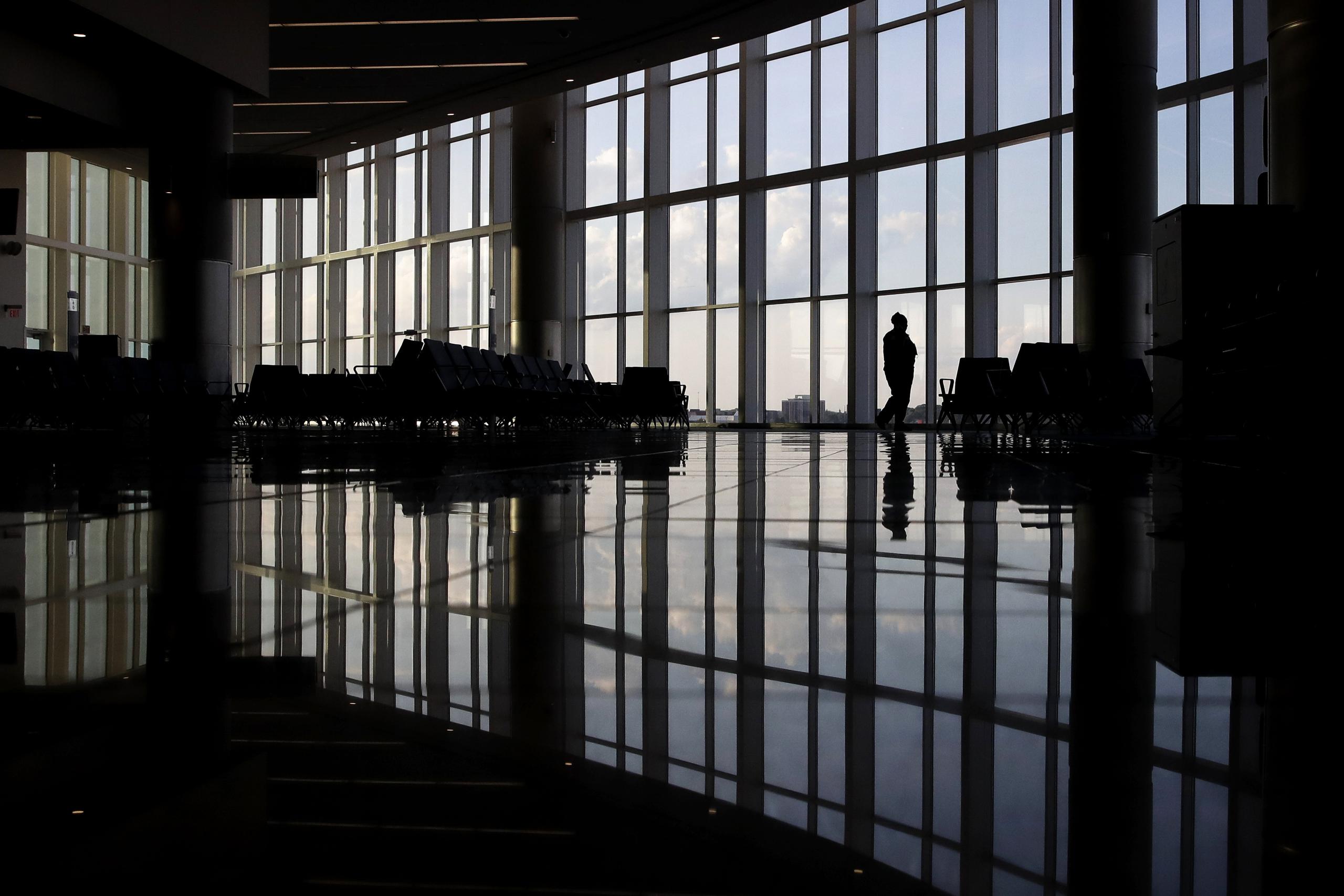 Una mujer mira por una ventana en una terminal casi vacía en el aeropuerto de Atlanta.