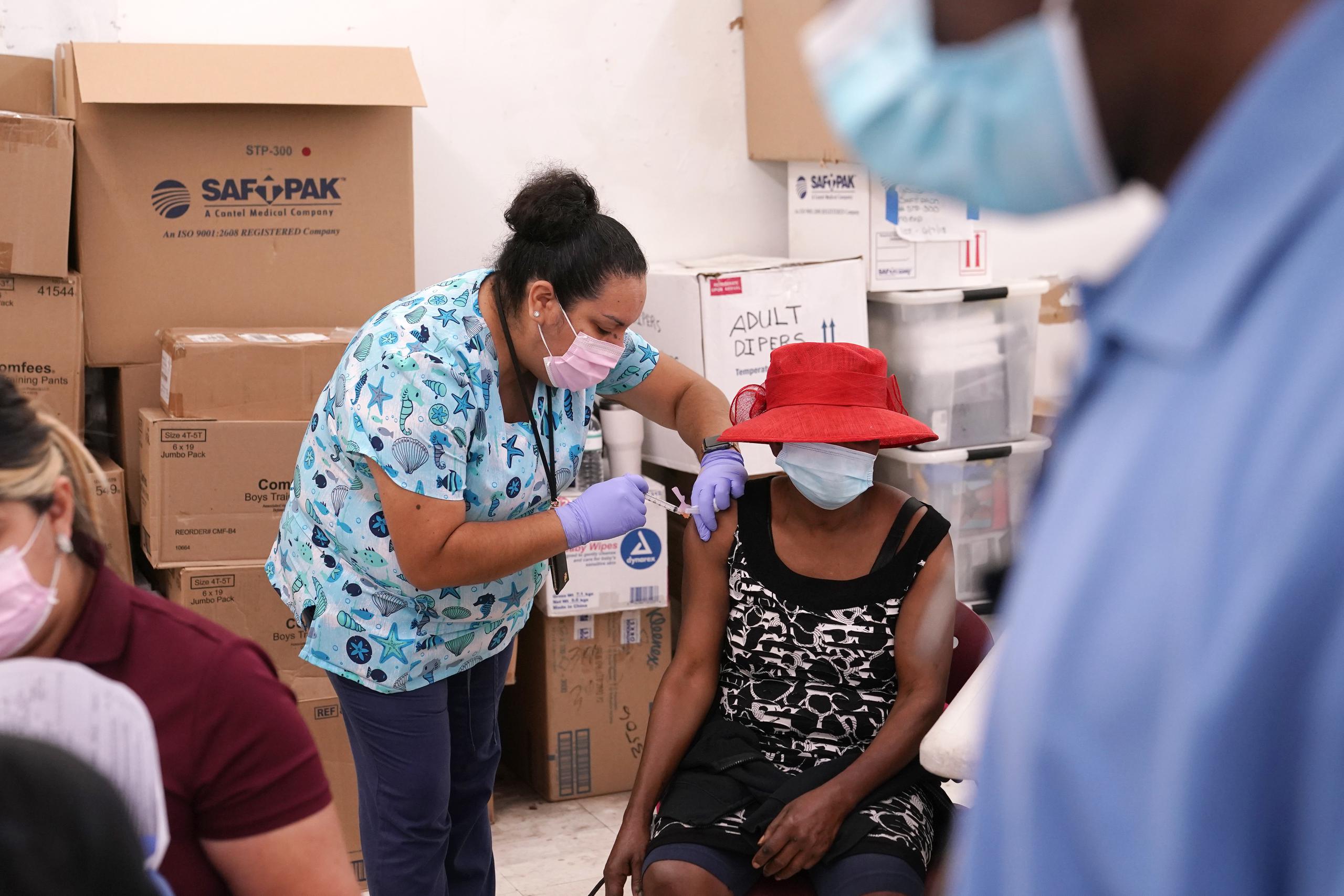 La enfermera Ashleigh Velasco, aplica una vacuna de Johnson & Johnson contra el COVID-19 a Rosemene Lordeus, a la derecha, en una clínica a cargo de Health Network, en Immokalee, Florida.