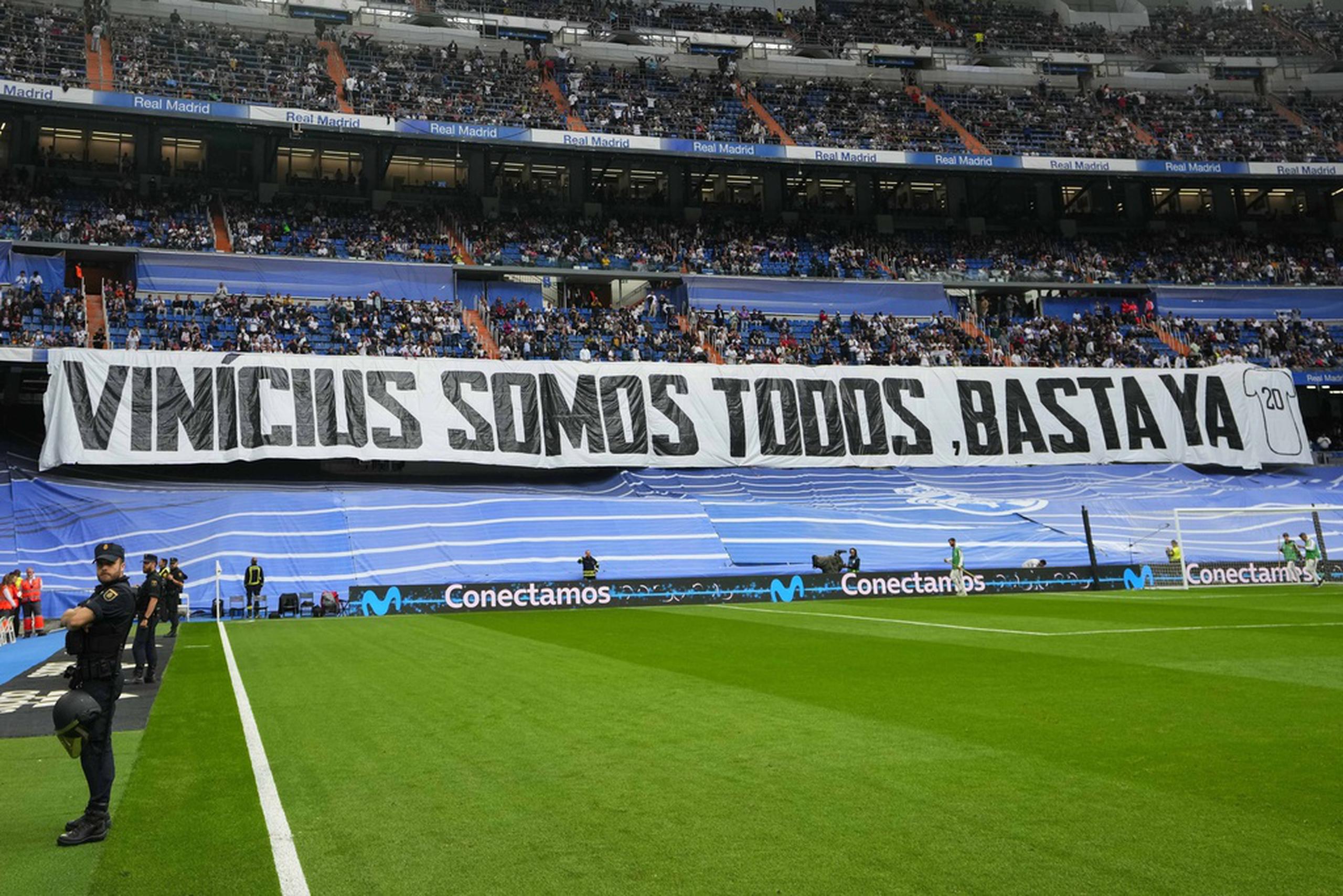 En la Liga española, espectadores despliegan la pancarta con la frase "Vinicius Somos Todos, Basta Ya" en el estadio Santiago Bernabéu, en defensa al jugador brasileño Vinicius Jr., quien ha sido objeto de burlas racistas en diferentes estadios en España.
