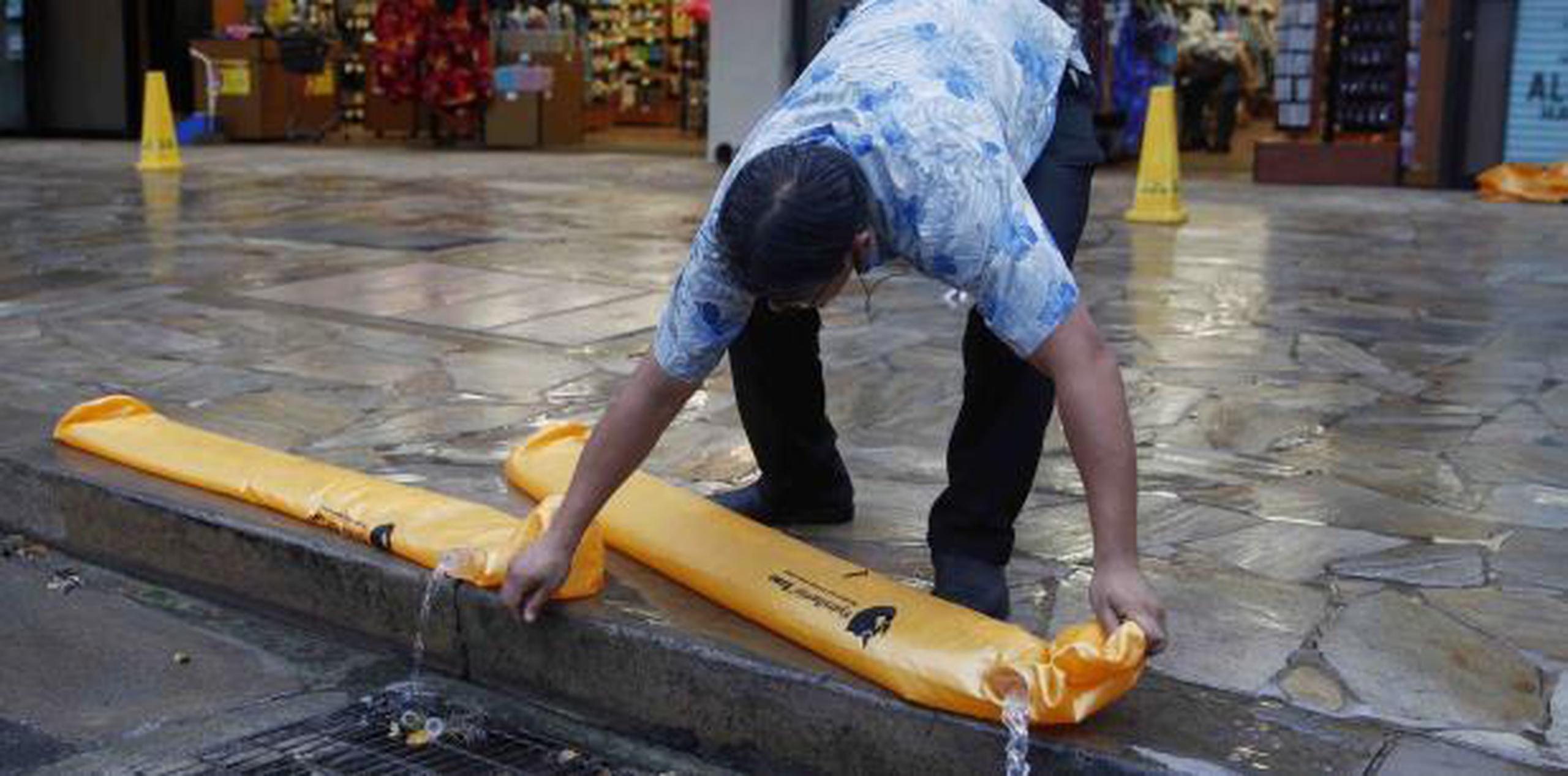 Kevin Pak vacía barreras hidráulicas, que se usan para bloquear agua similar a un saco de arena, mientras ayuda a reabrir una tienda ABC en Waikiki Beach, Honolulu. (AP / John Locher)