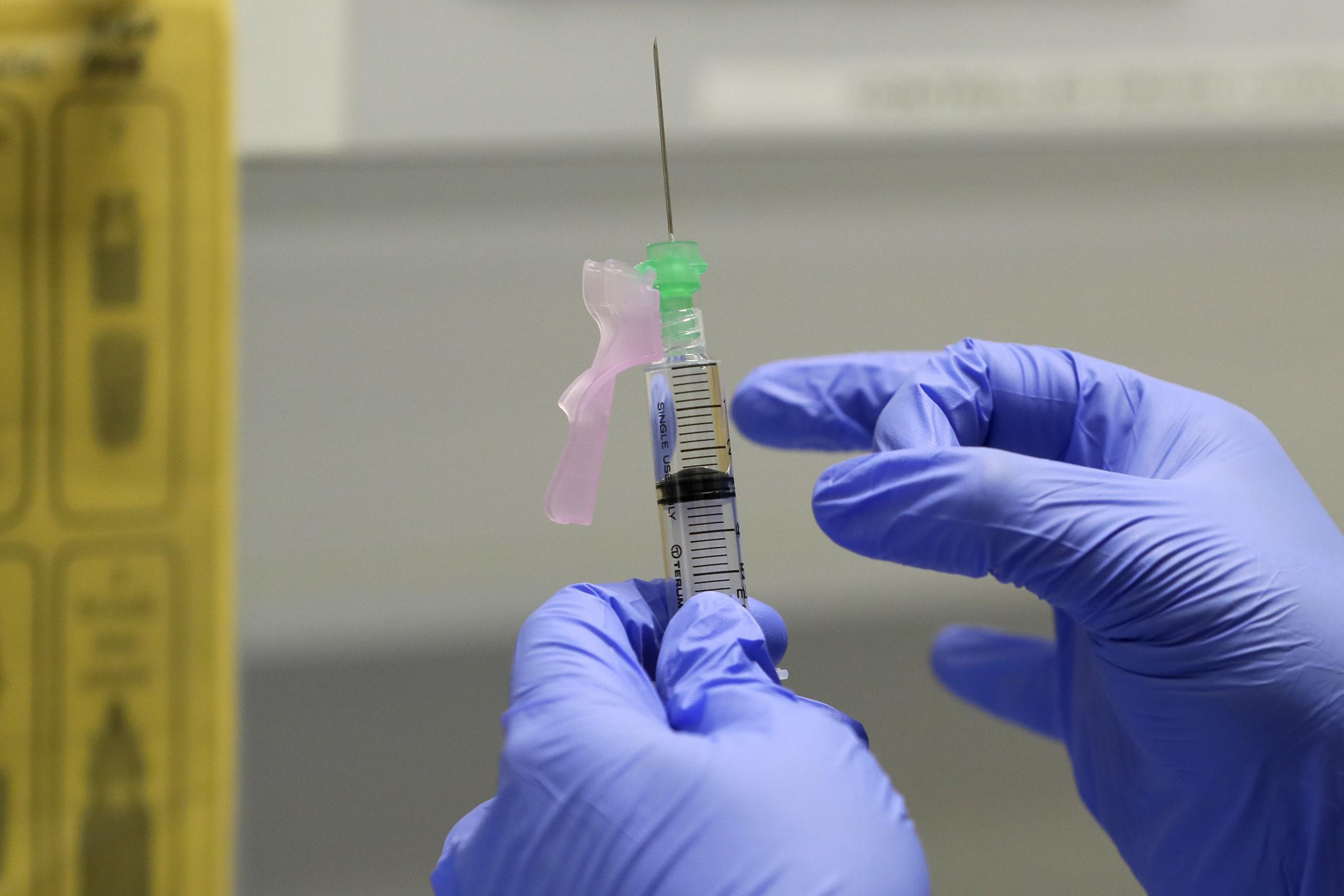 Personal médico prepara una dosis de vacuna contra COVID-19 como parte de un ensayo clínico en Londres.