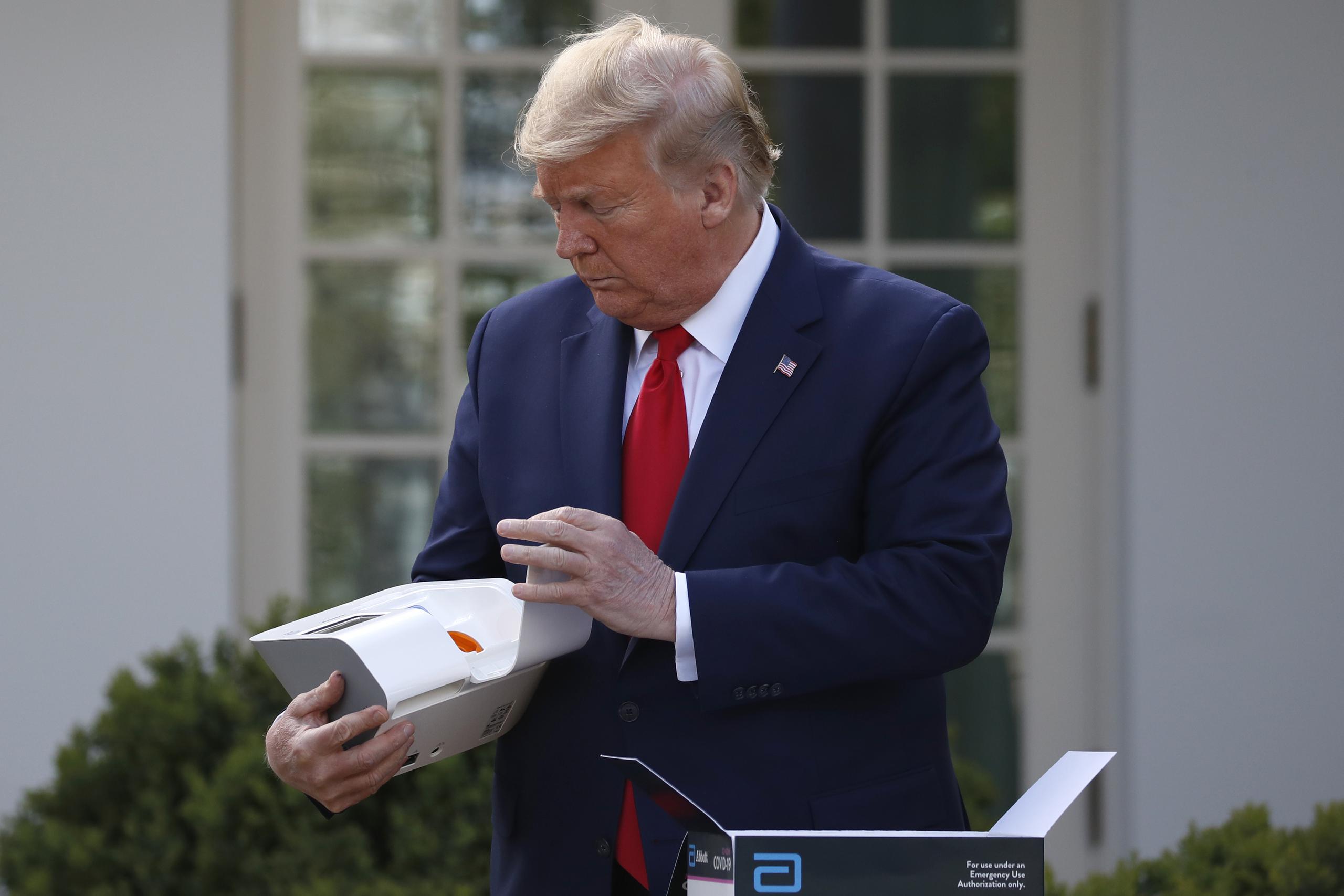 Donald Trump abre una caja que contiene una prueba de 5 minutos para detectar Covid-19 de Abbott Laboratories en la Casa Blanca, en Washington