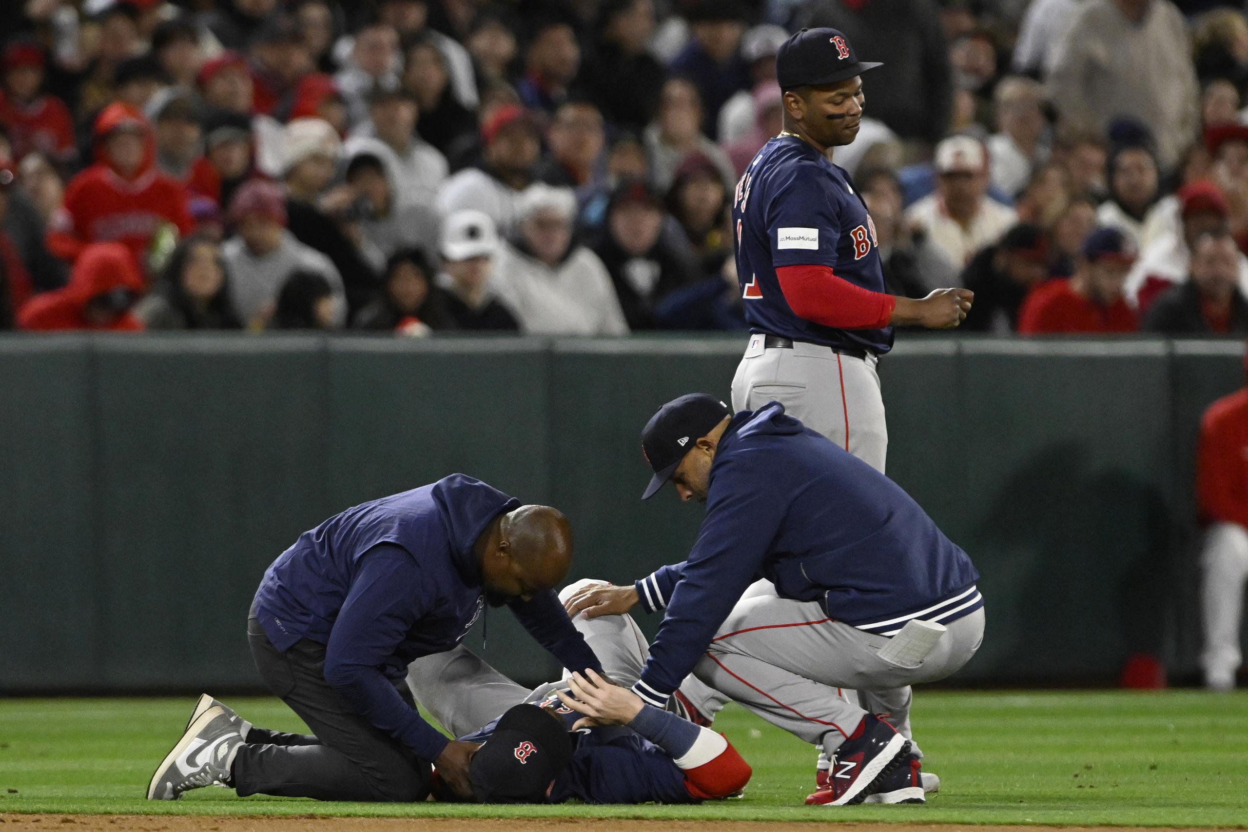 Trevor Story, campocorto de los Red Sox, recibe atención de un médico y del mánager Alex Cora, tras lastimarse en el encuentro del pasado viernes.