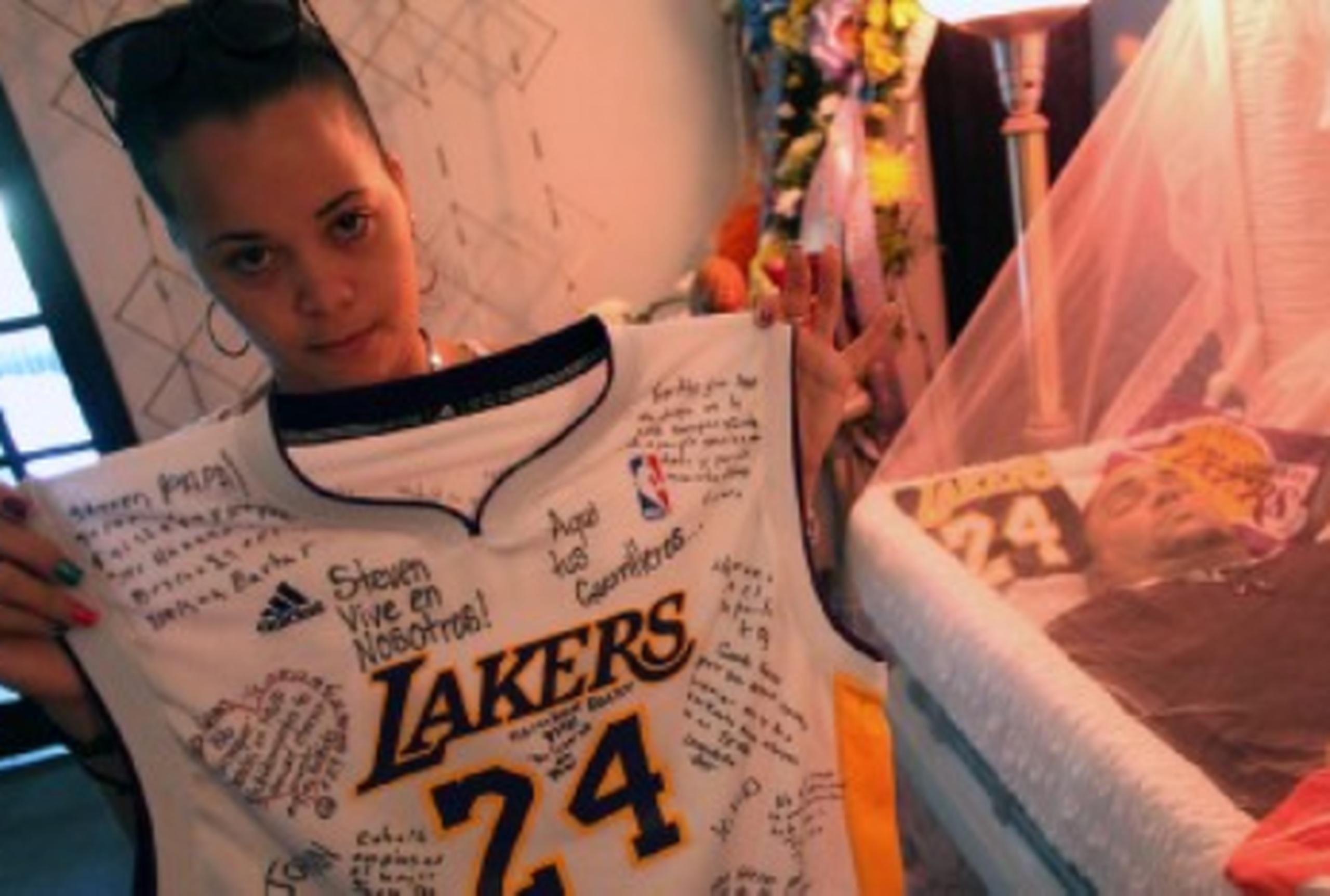 La novia de Steven, Tamara Díaz, sostiene la camisa del equipo de Los Angeles Lakers, el favorito del fallecido. En la camisa amigos y familiares escribieron mensajes. (GFR Media / Olimpo Ramos) 

