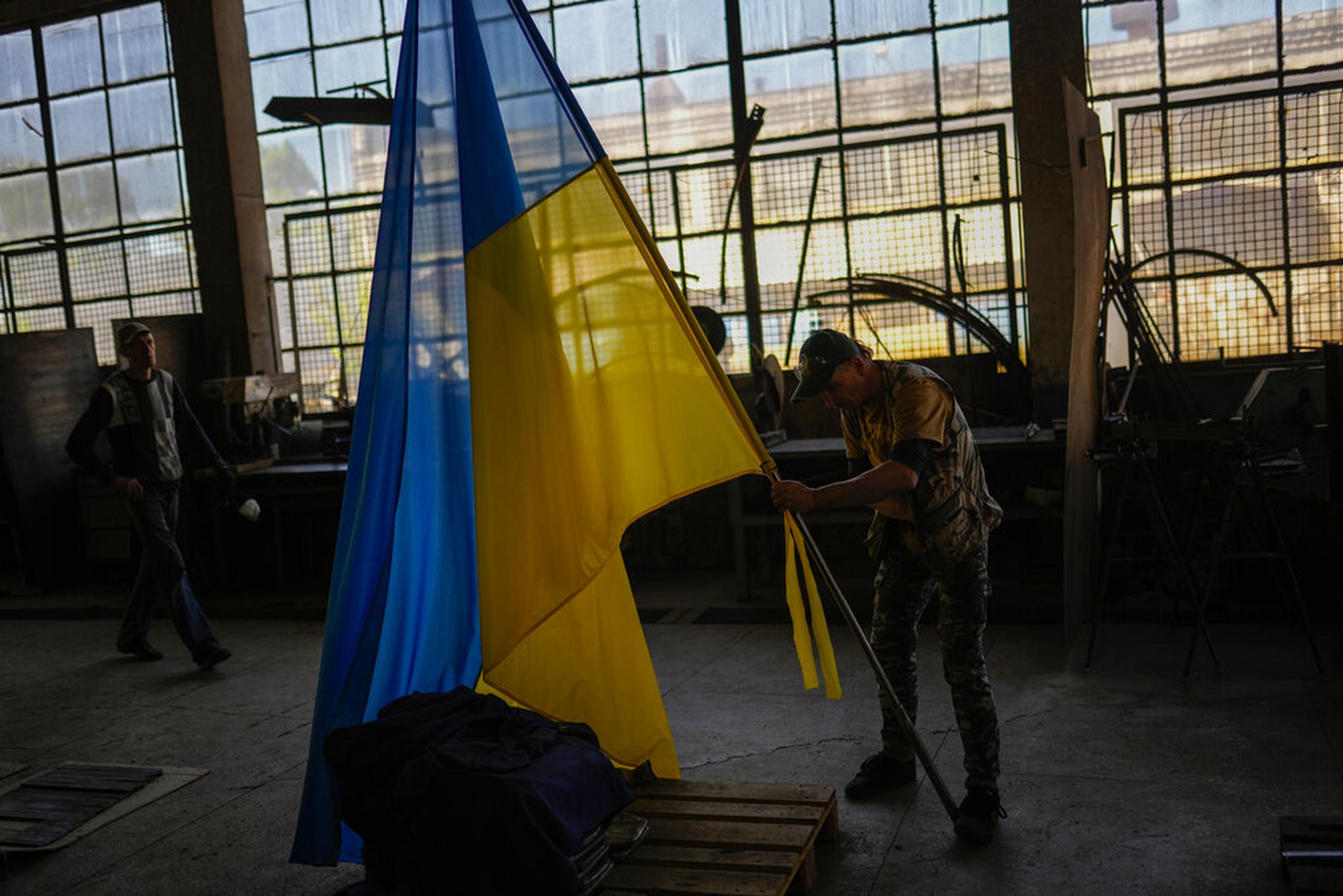 Un voluntario coloca una bandera de Ucrania en una instalación que produce material para soldados ucranianos en Zaporizhzhia, Ucrania, el 6 de mayo de 2022.