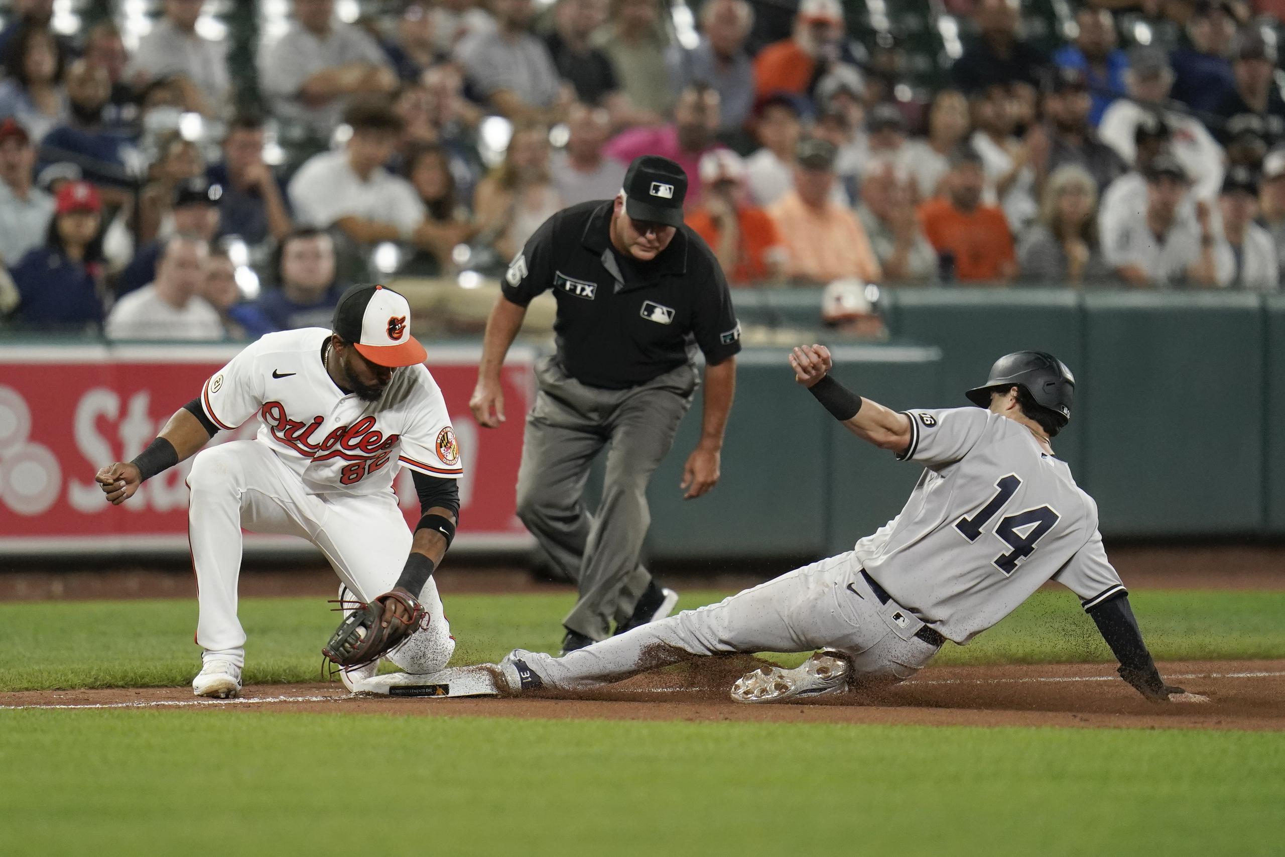 Tyler Wade, de los Yankees de Nueva York, se desliza a salvo en tercera base mientras Kelvin Gutiérrez, antesalista de Baltimore, recibe el disparo.