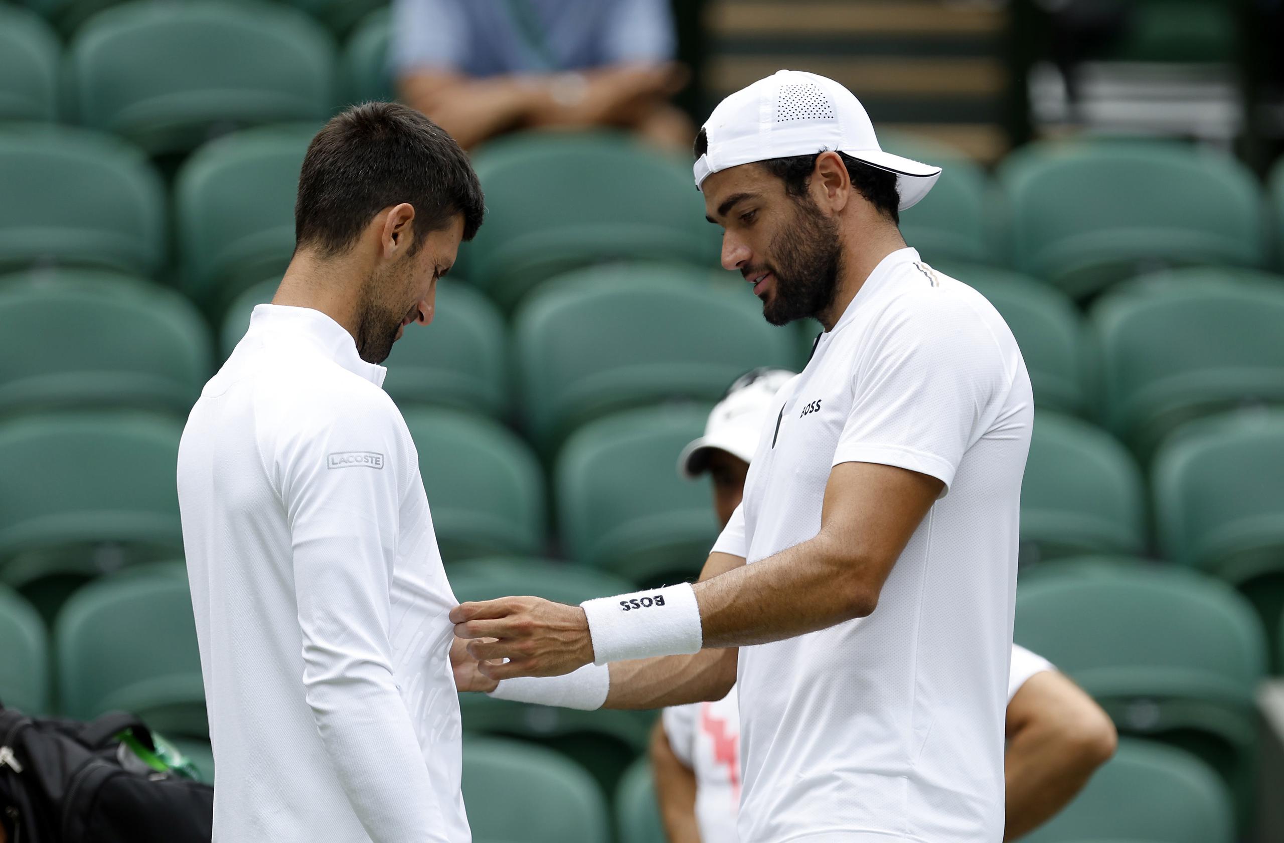 Matteo Berrettini revisa el atuendo de Novak Djokovic durante una práctica en la Cancha Central de Wimbledon, el 23 de junio de 2022. (Steven Paston/PA vía AP)