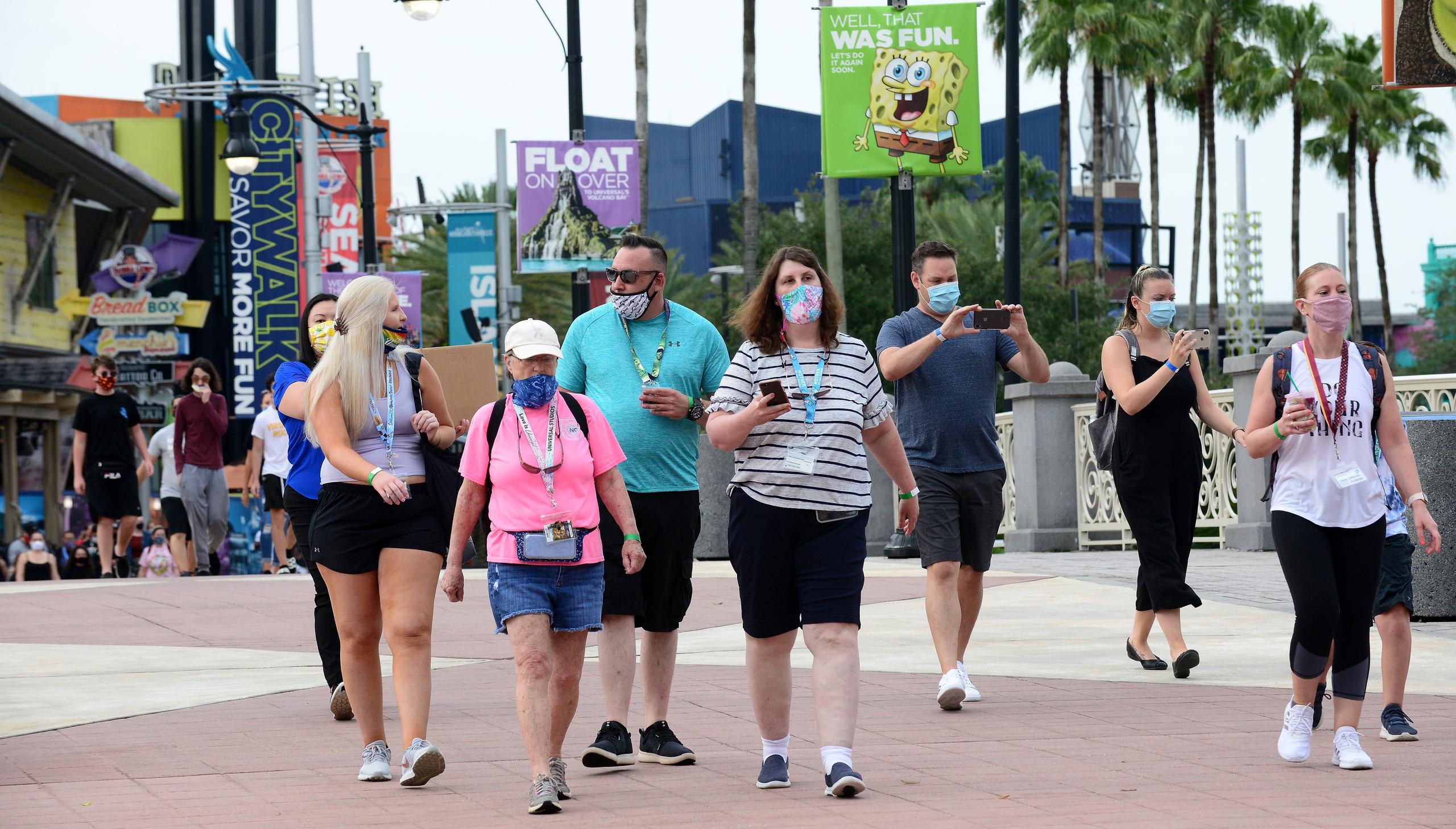 Varias personas con mascarillas caminan por el parque temático de Universal Studios en Orlando.