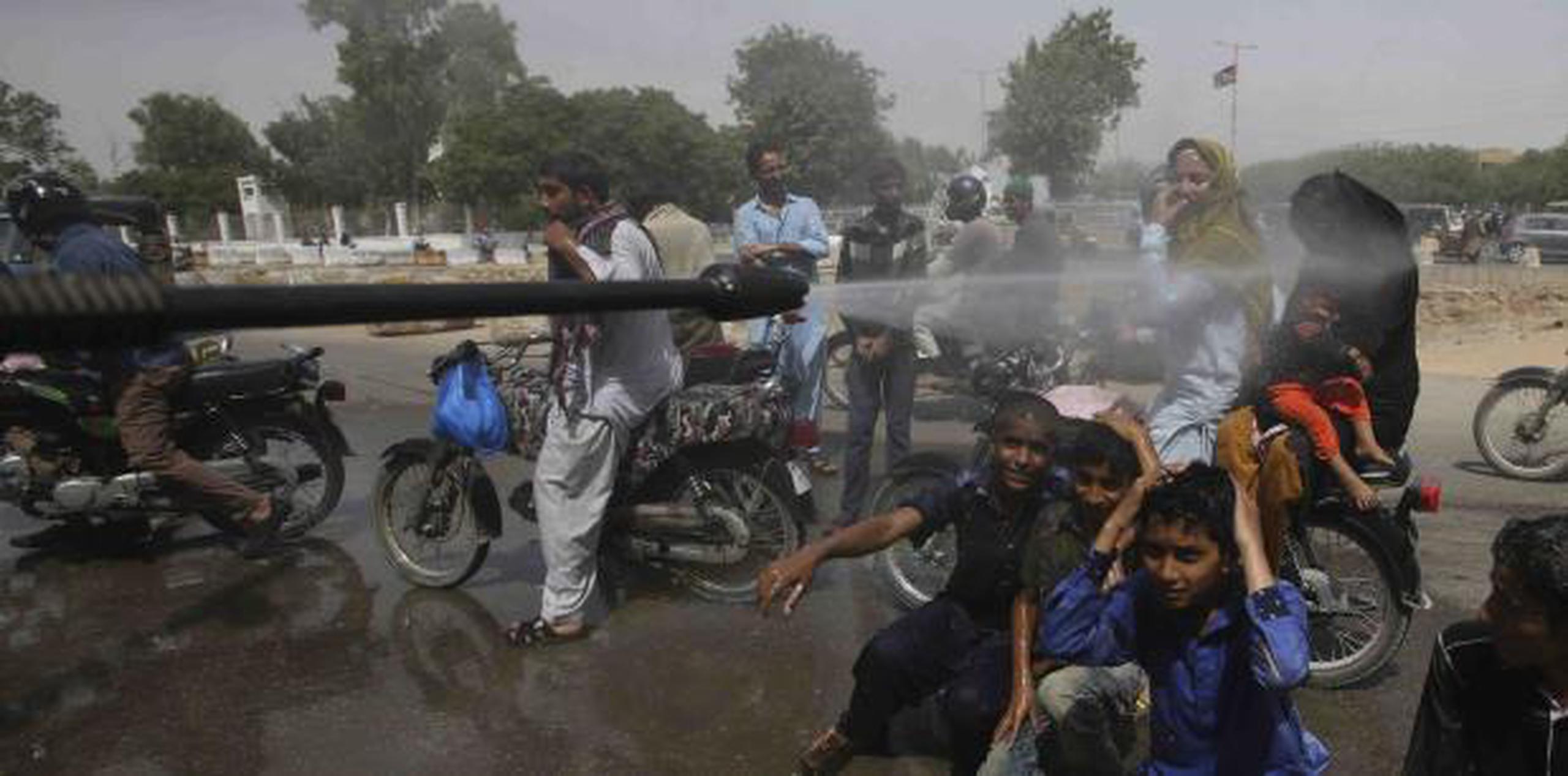 Voluntarios dispersan agua a ciudadanos en medio de intensa ola de calor. (AP)