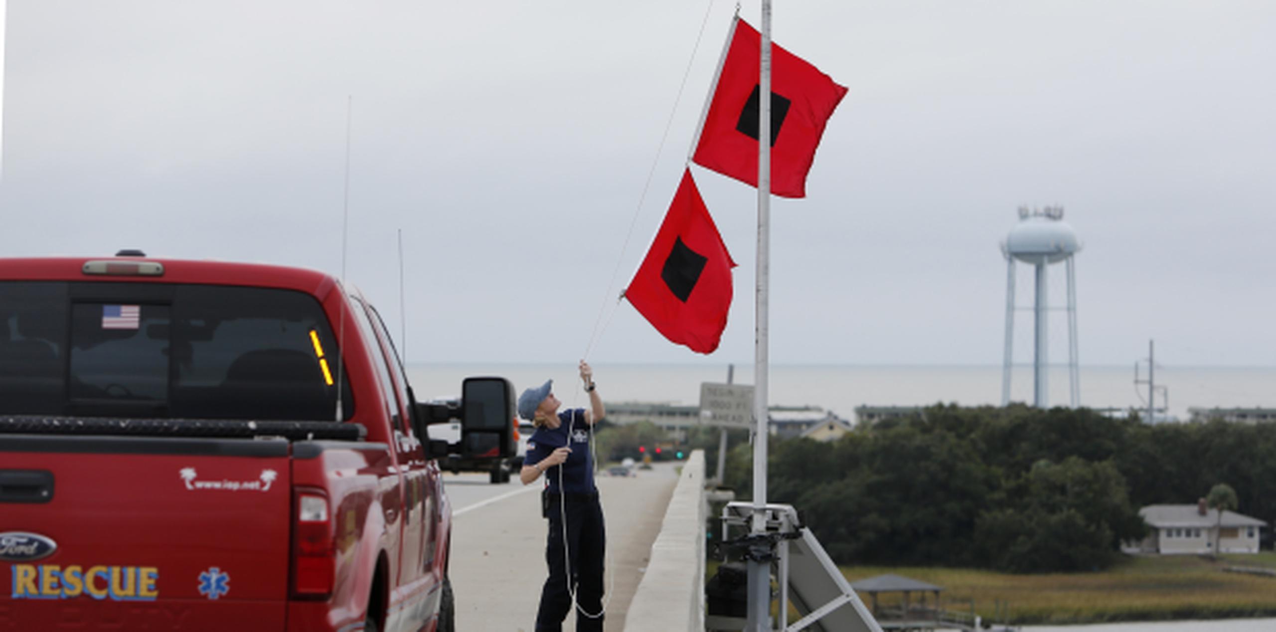 El chief Ann Graham, junto al cuerpo de bomberos de la Isla de Palmas, coloca dos banderas de aviso de huracán en el puente de Isla de las Palmas ante el paso de Matthew por Carolina del Sur. (AP / Mic Smith)