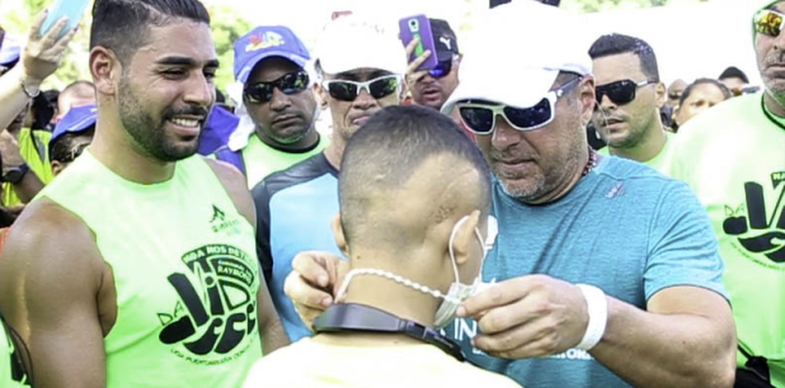 Raymond Arrieta le coloca un rosario a un niño paciente de cáncer con el que compartió en su caminata. (Especialpara PrimeraHora/JuanLuisValentín)