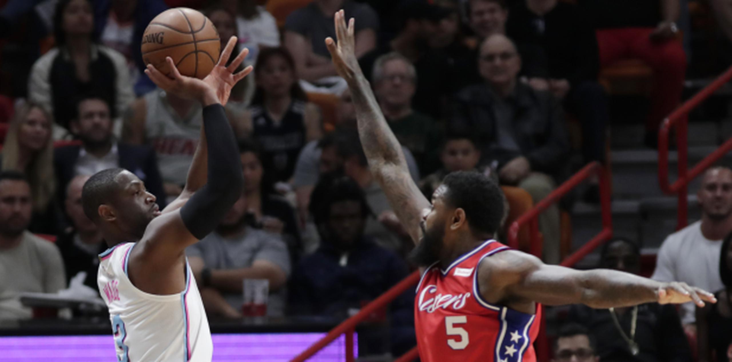 Dwyane Wade, del Heat de Miami, intenta un triple frente a Amir Johnson, de los 76ers de Filadelfia, durante la primera mitad del encuentro realizado este jueves. (AP)