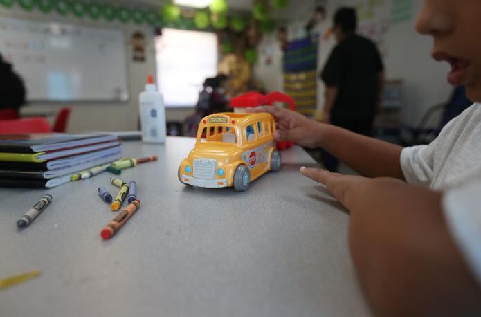 Un estudiante juega con una guagua de juguete en un salón de clases.