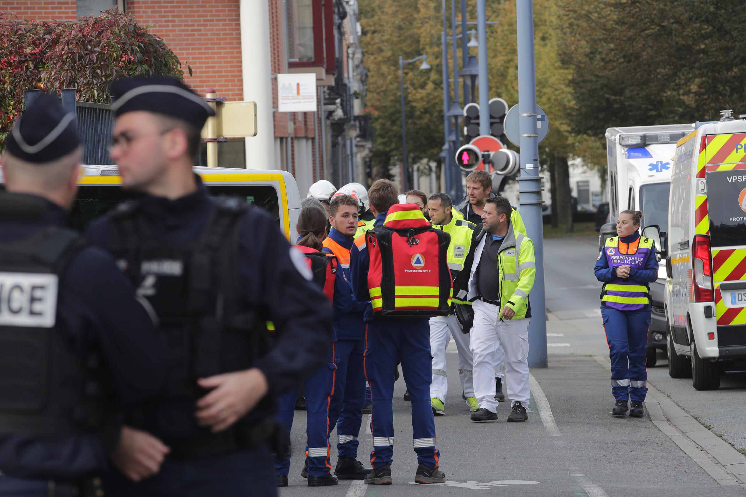 Police officers and rescue workers wait near the Gambetta high school during a bomb alert Monday, Oct. 16, 2023 in Arras, northern France. French authorities say the high school where a teacher was fatally stabbed in an attack last week has been evacuated over a bomb alert, as France's President cut short travel plans abroad to host a security meeting Monday.(AP Photo/Michel Spingler)