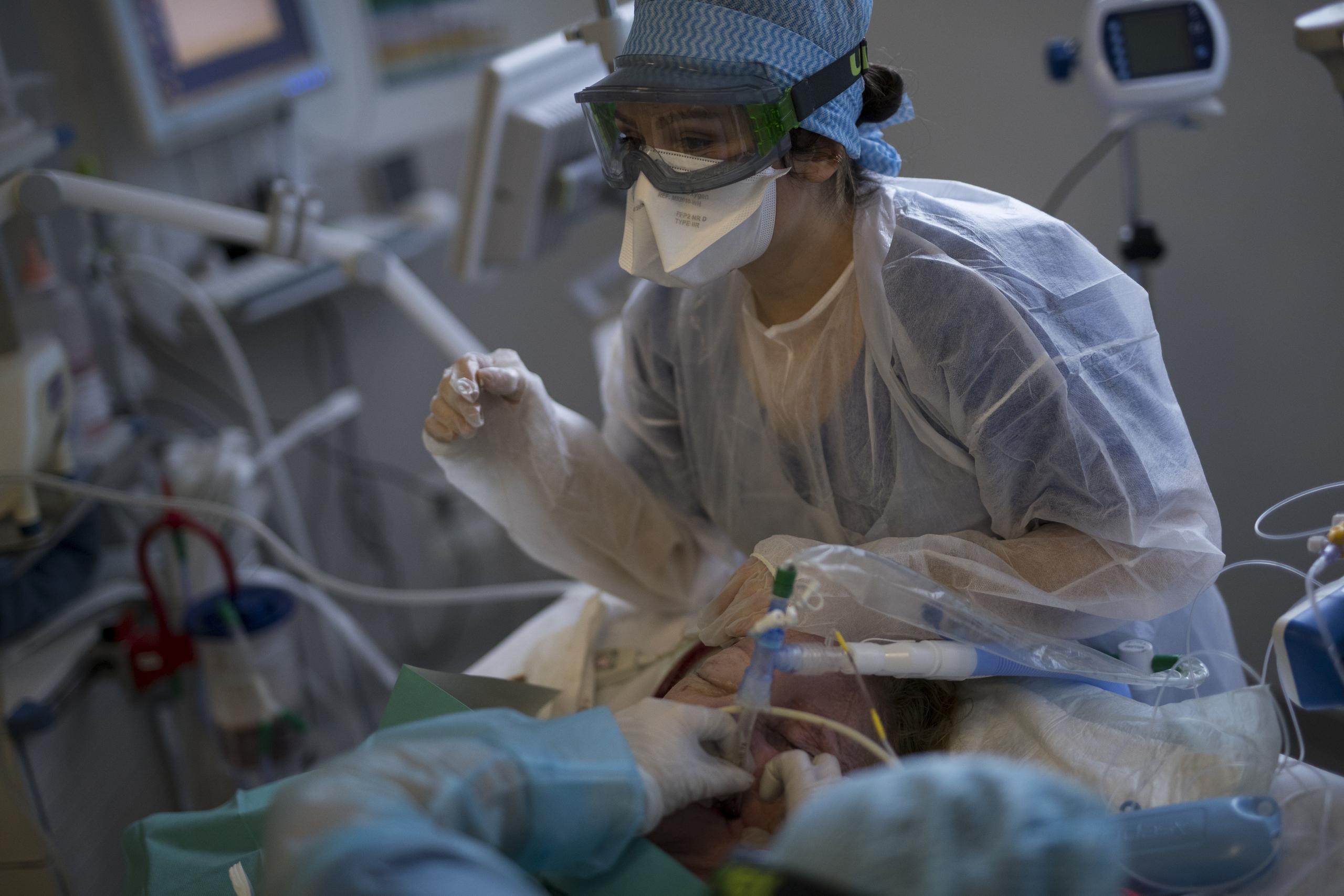 Efermeras vuelven a colocar un respirador, después de limiparlo, a un paciente de COVID-19 en la UCI del hospital La Timone de Marsella.