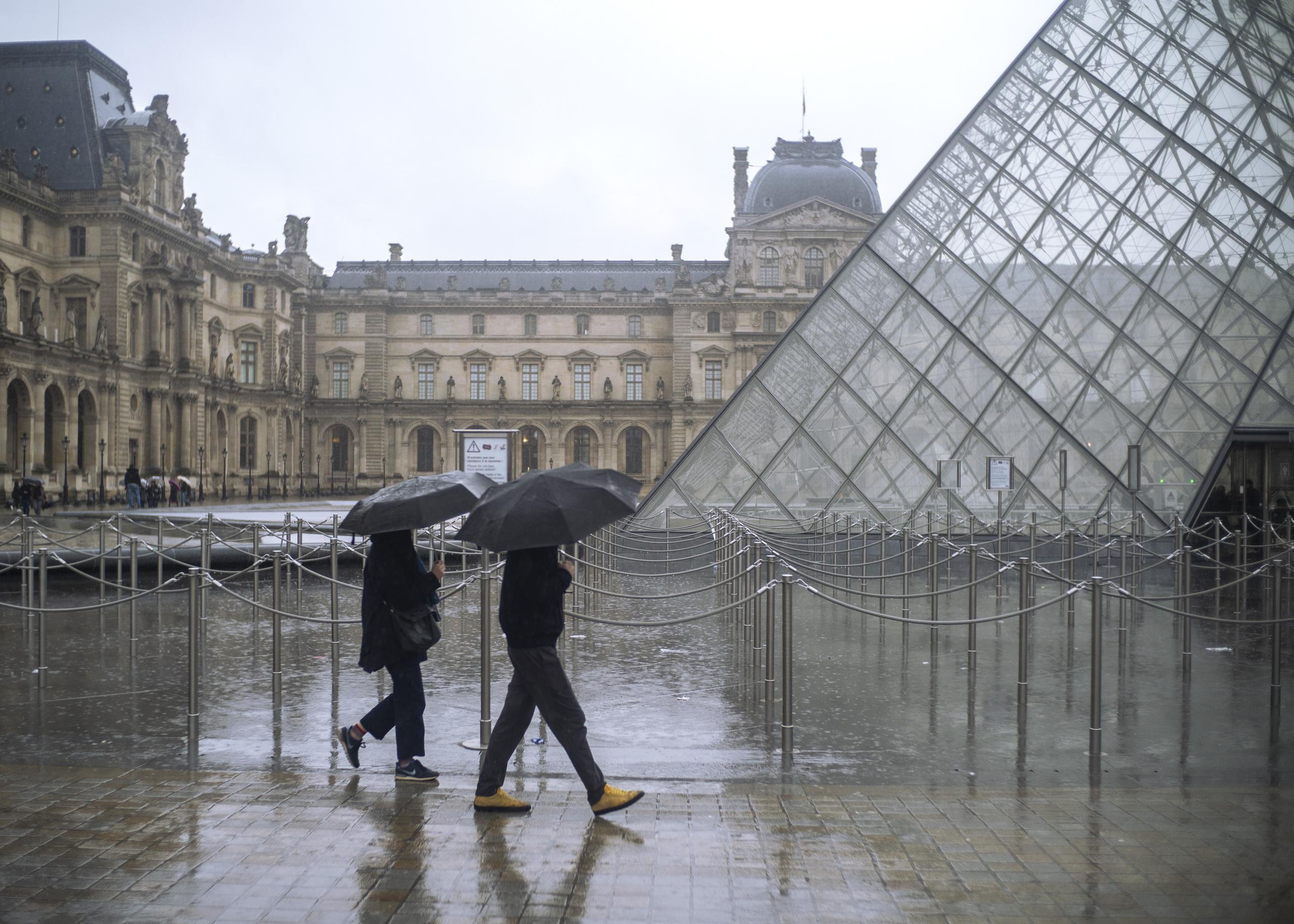 Gente pasa junto al Museo del Louvre en París que permanecerá cerrado por el momento.