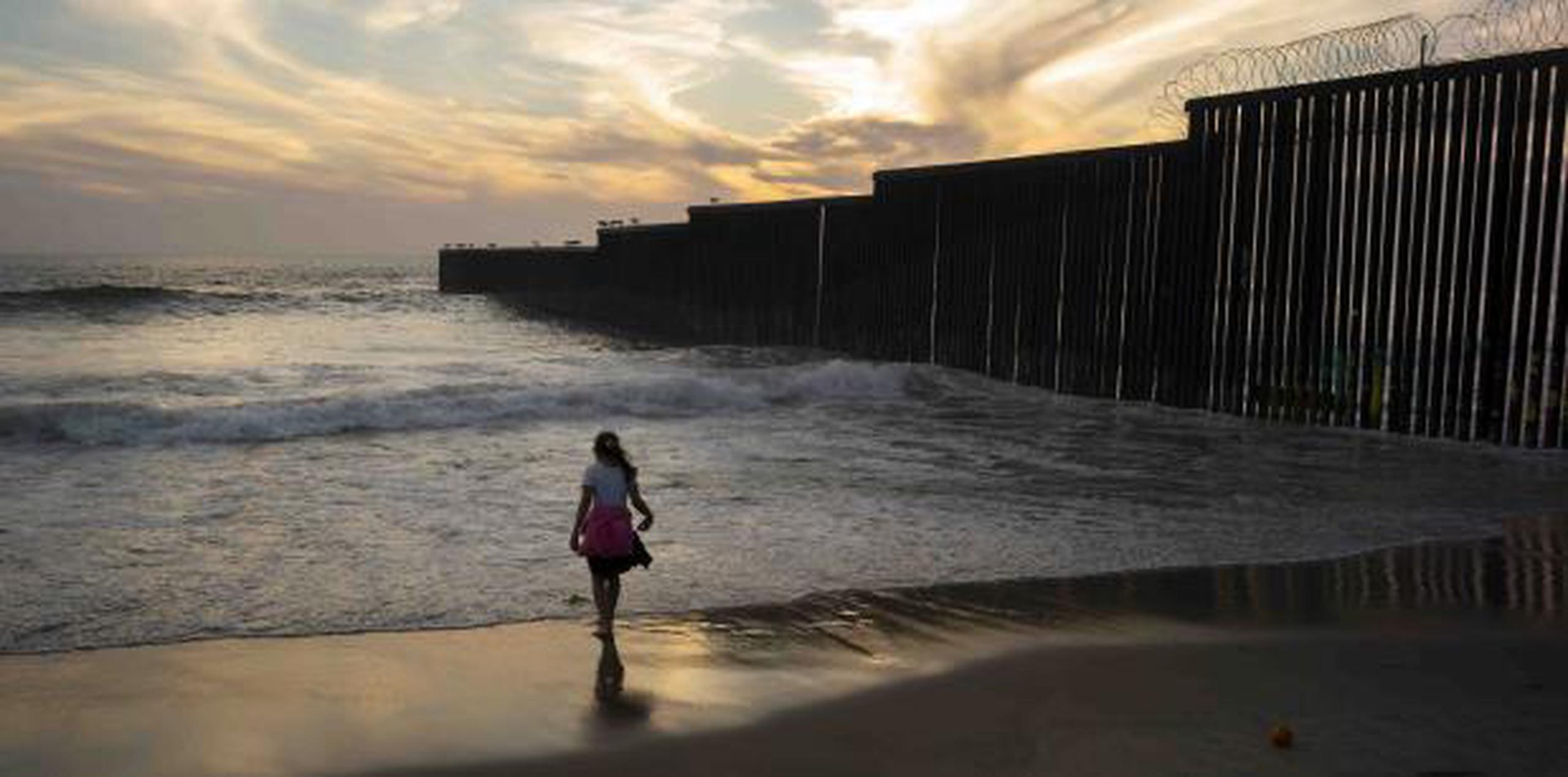 Una niña juega cerca de un muro existente entre San Diego y Tijuana. (AP)