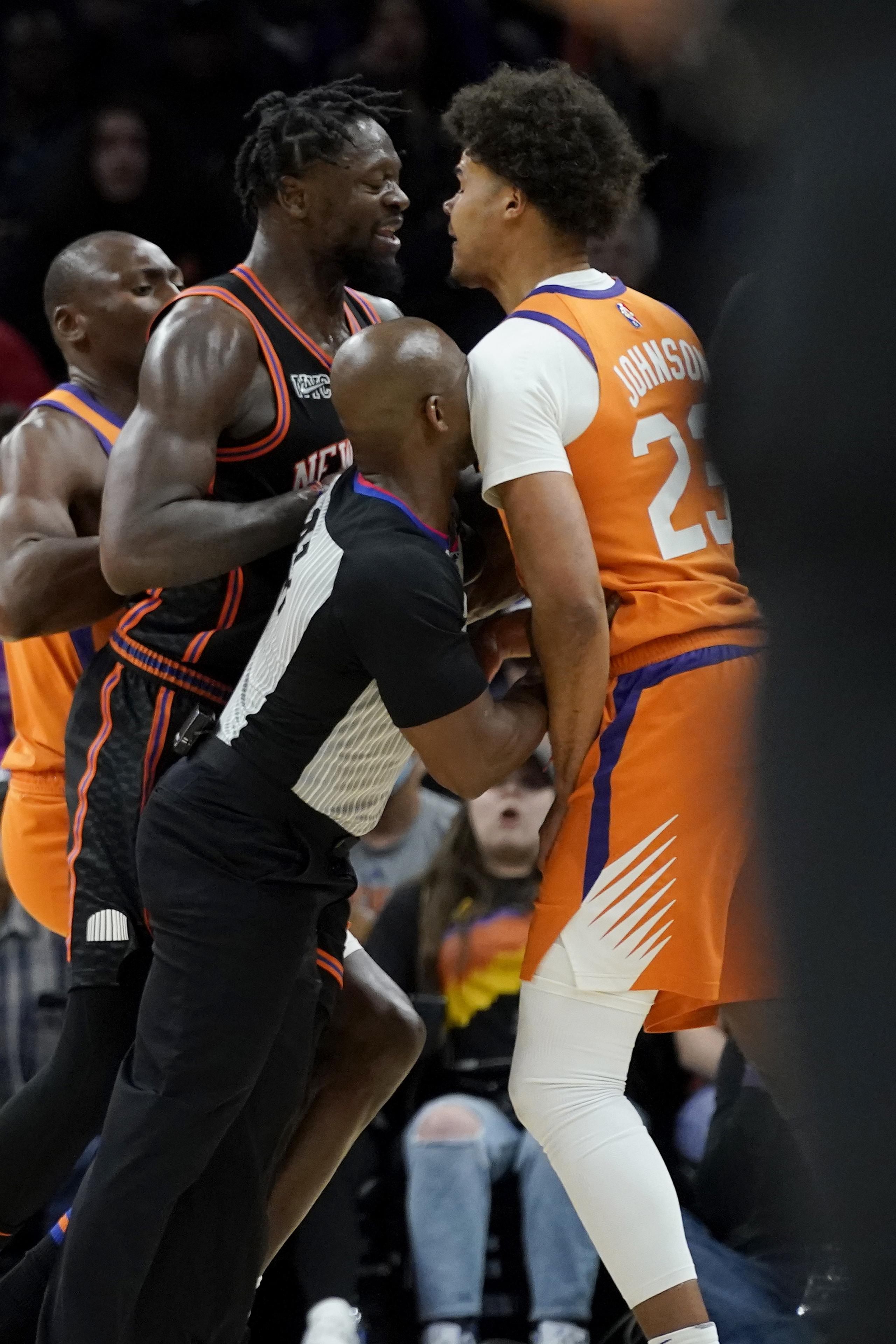 El alero Cameron Johnson (23), de los Suns de Phoenix, y Julius Randle, alero de los Knicks de Nueva York, son separados por un árbitro durante la segunda mitad del juego de baloncesto de la NBA, el viernes 4 de marzo de 2022, en Phoenix. Randle fue expulsado después de la jugada y los Suns derrotaron a los Knicks 115-114. (AP Foto/Matt York)