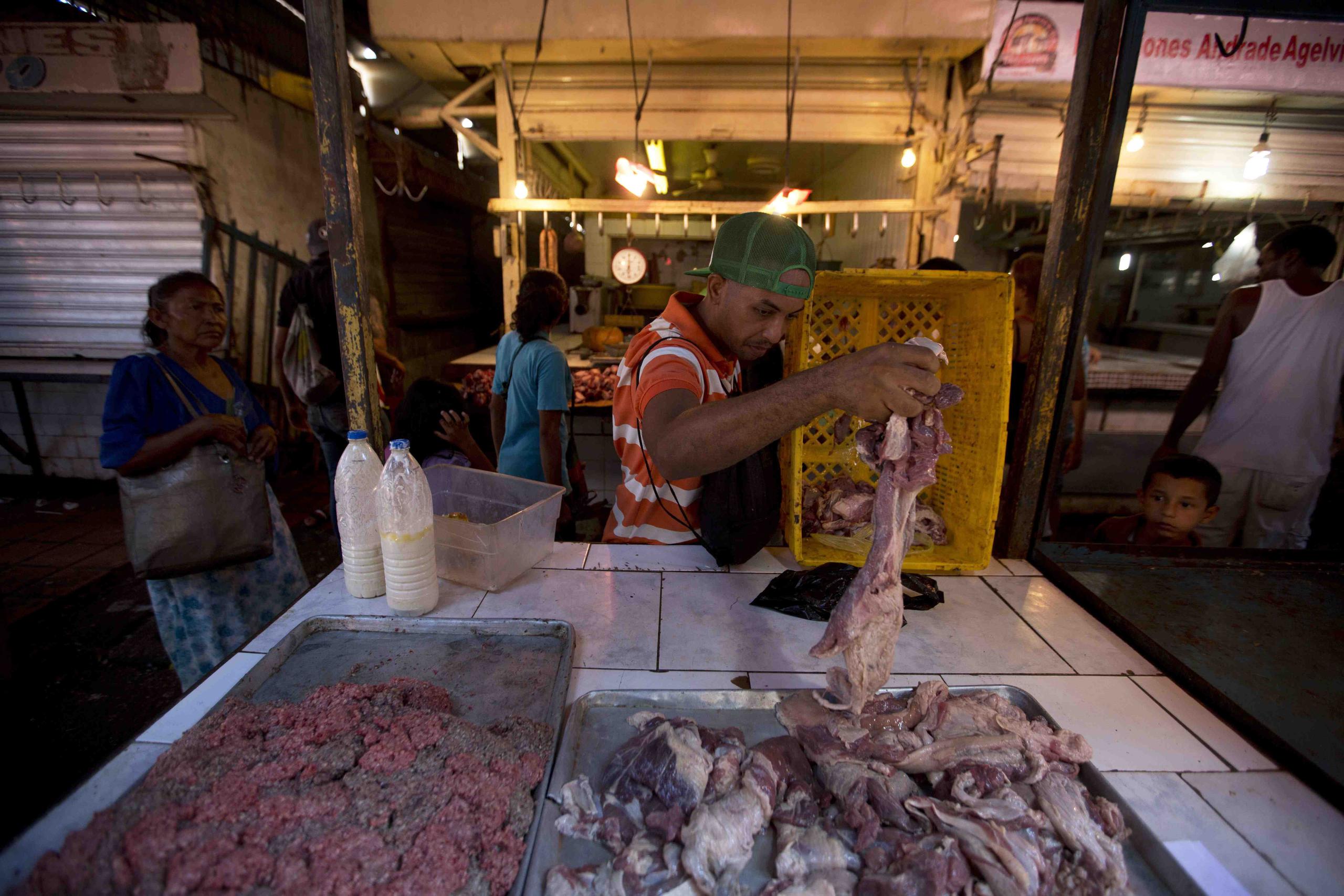 El carnicero Johel Prieto coloca pedazos de carne podrida en una bandeja para vender. (AP / Fernando Llano)