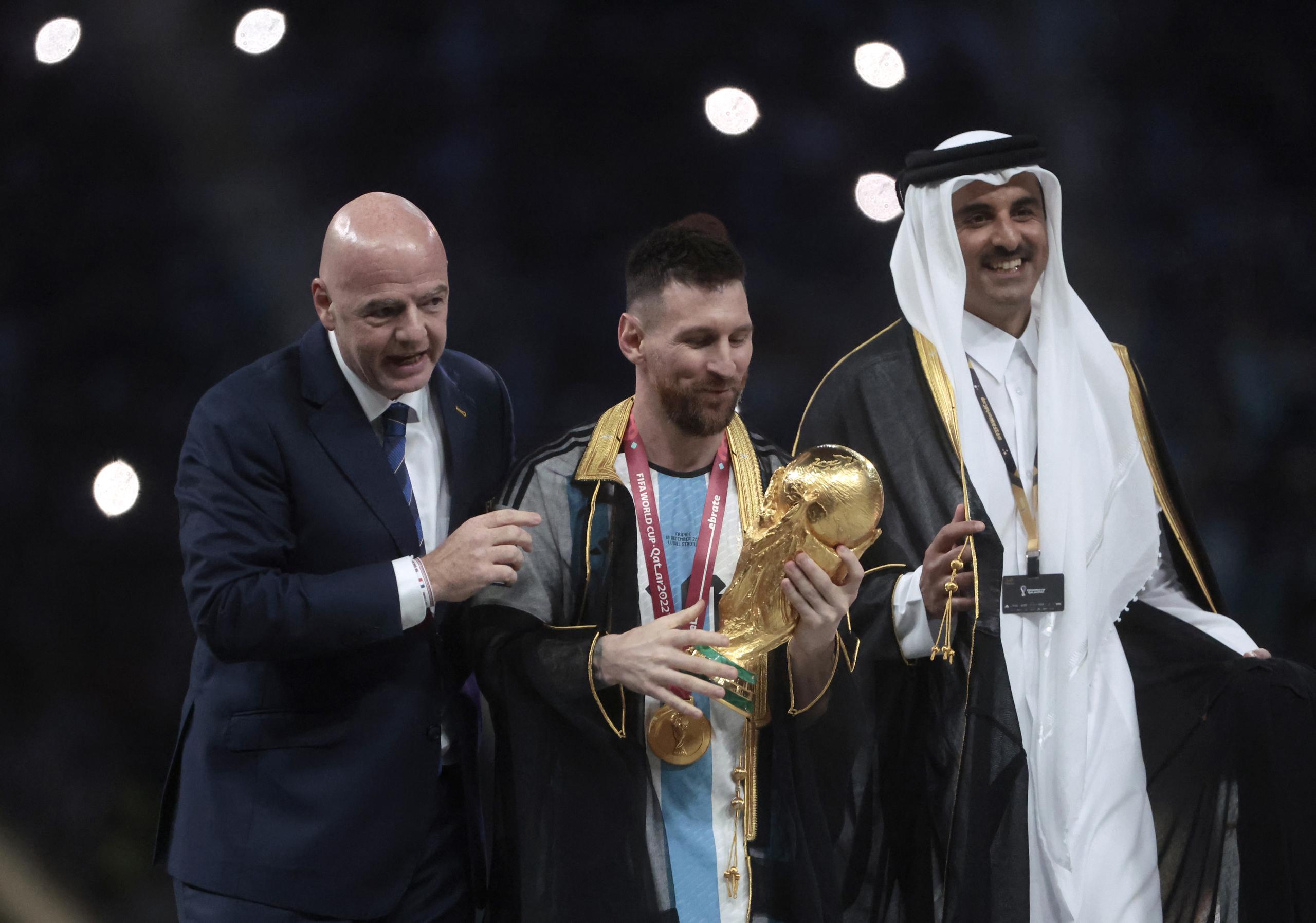 Lionel Messi posa con el trofeo de la Copa del Mundo junto a el presidente de la FIFA Giovanni Vincenzo (izquierda) y el Emir del Estado de Catar, Tamim bin Hamad Al Thani.