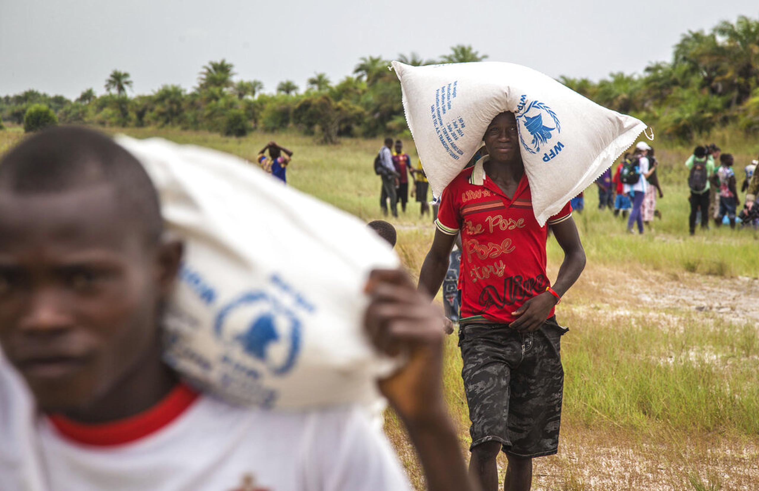 Personas cargan alimentos proporcionados por el Programa Mundial de Alimentos, en la Isla de Sherbo, Sierra Leona.