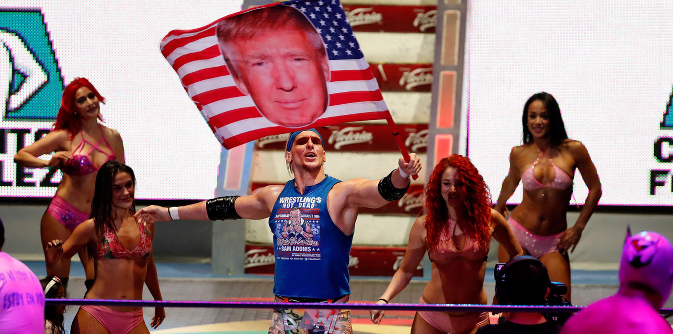 La multitud en la Arena México de la capital estalla en gritos, abucheos, burlas y chiflidos sarcásticos mientras Adonis aparece con un bronceado anaranjado, al estilo Trump, y el cabello rubio mientras agita una bandera estadounidense que tiene una foto de Trump. (AP)