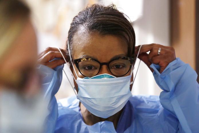 Una terapeuta respiratoria se coloca una segunda mascarilla sobre la máscara N95, en la unidad de cuidados intensivos de COVID-19 en un hospital en Seattle.